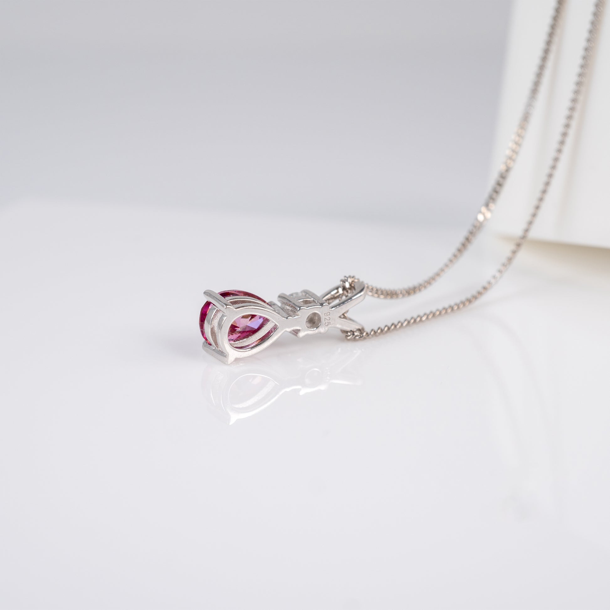Teardrop pink moissanite pendant necklace laid flat with chain