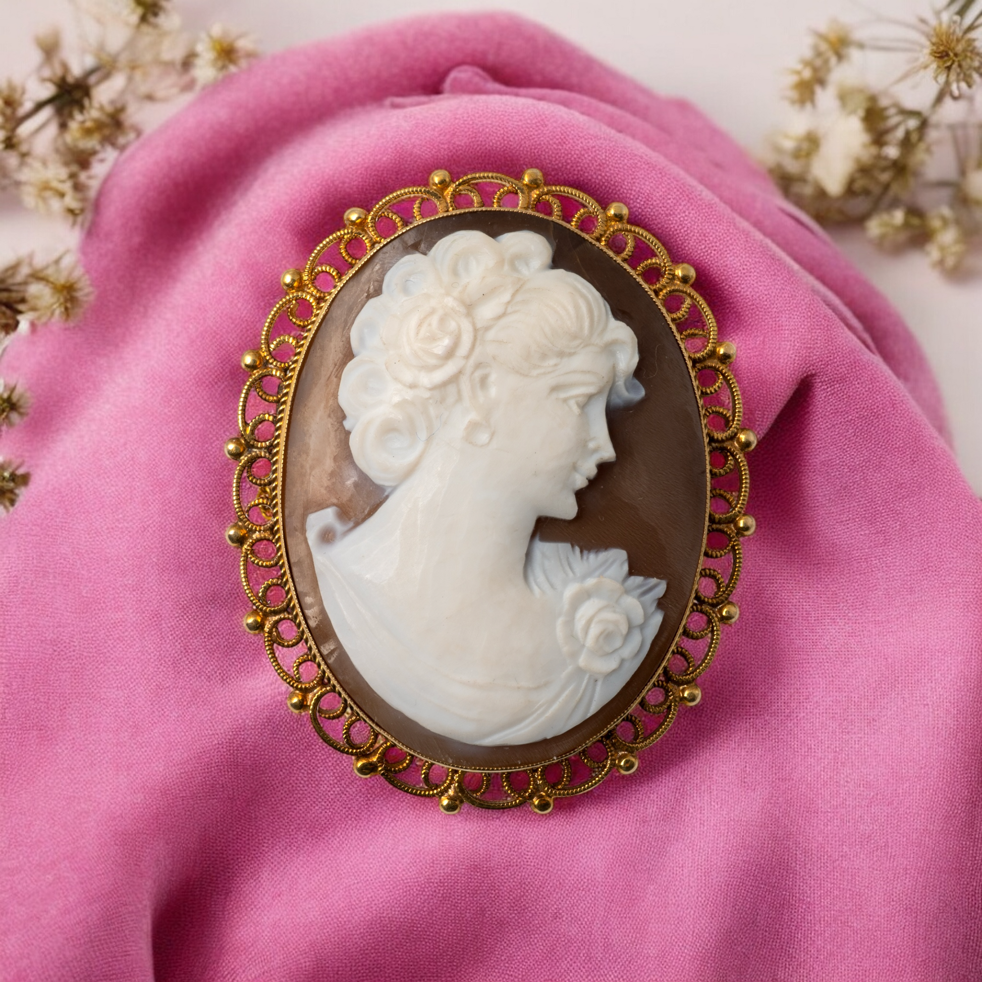 Elegant vintage cameo brooch on a fabric backdrop, highlighting intricate goldwork