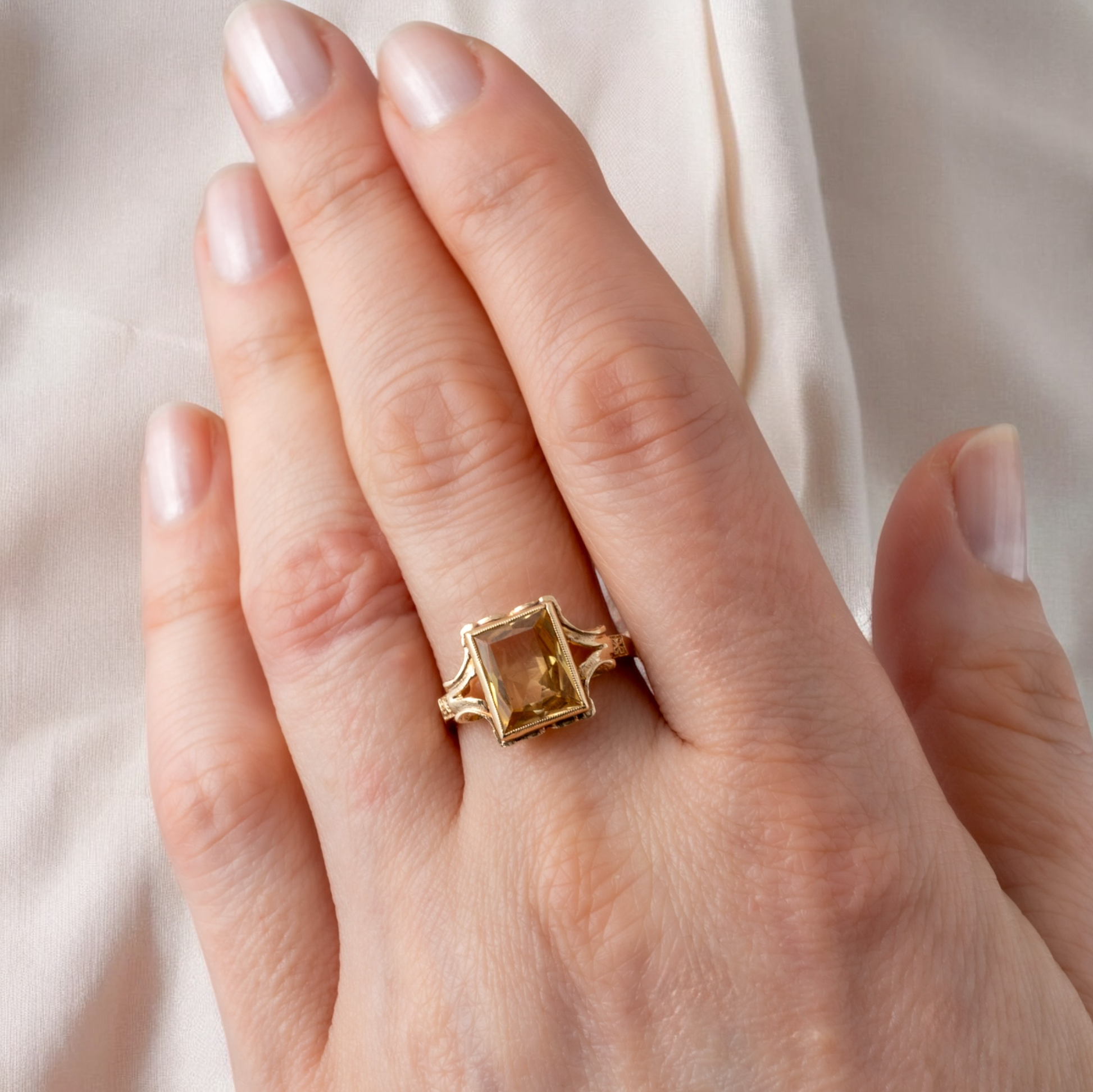 Vintage pale citrine ring on a woman's hand, showcasing its rectangular gemstone and milgrain border