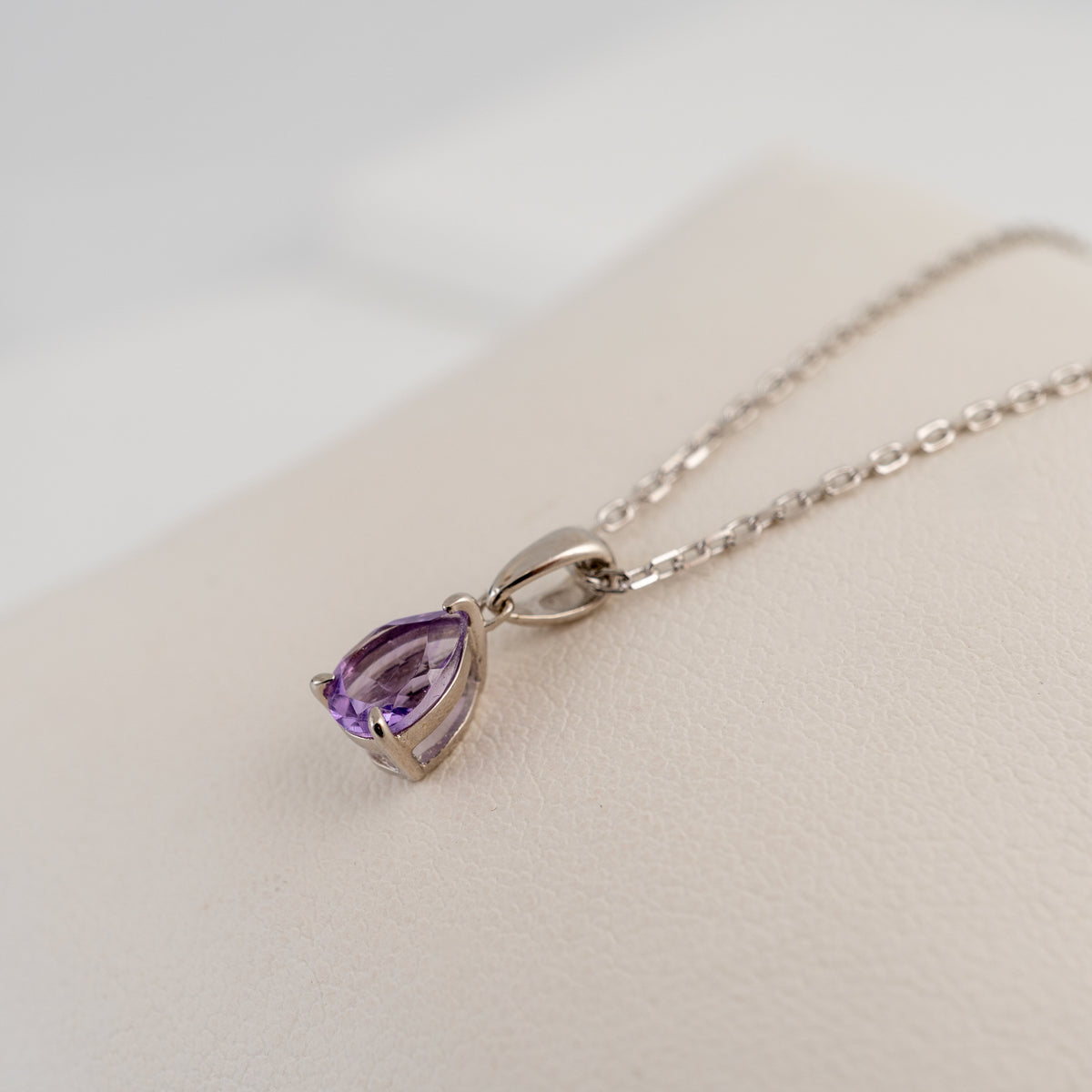 Natural pear cut amethyst pendant side view showing the smooth sterling silver bail