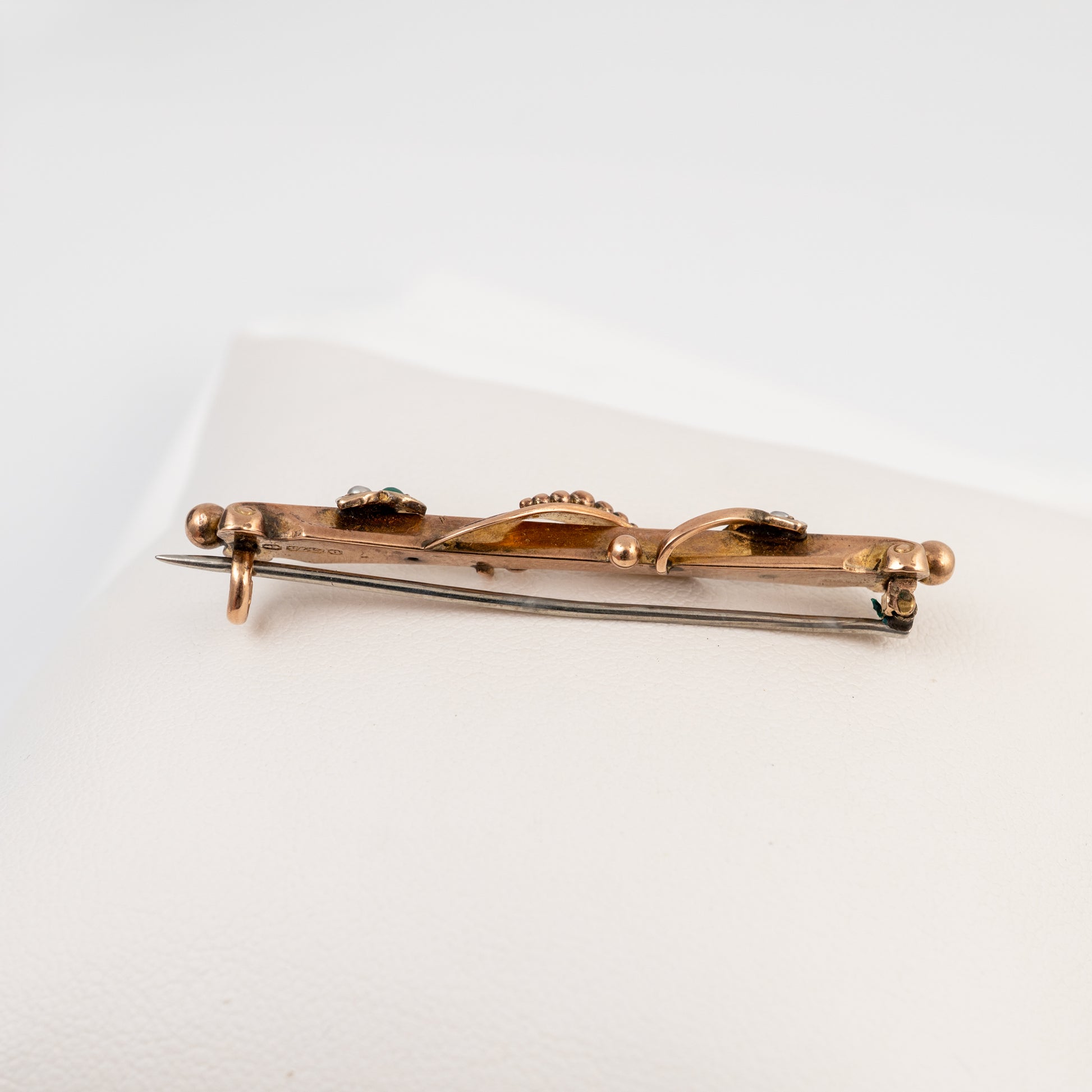 A vintage gold-toned pin with a butterfly motif and small dark stone accents, displayed on a white textured surface.