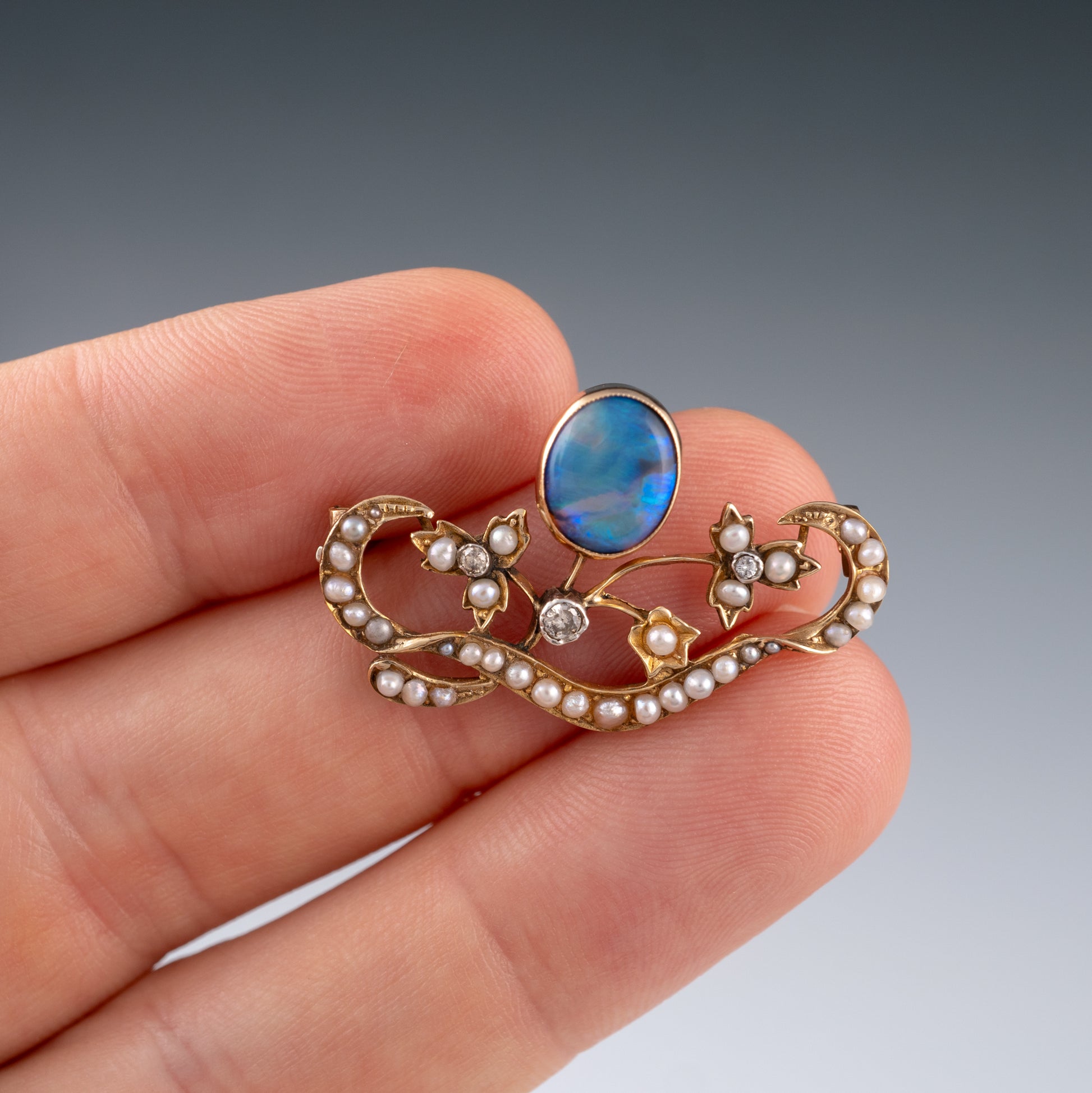 Antique opal brooch shown in hand for size scale