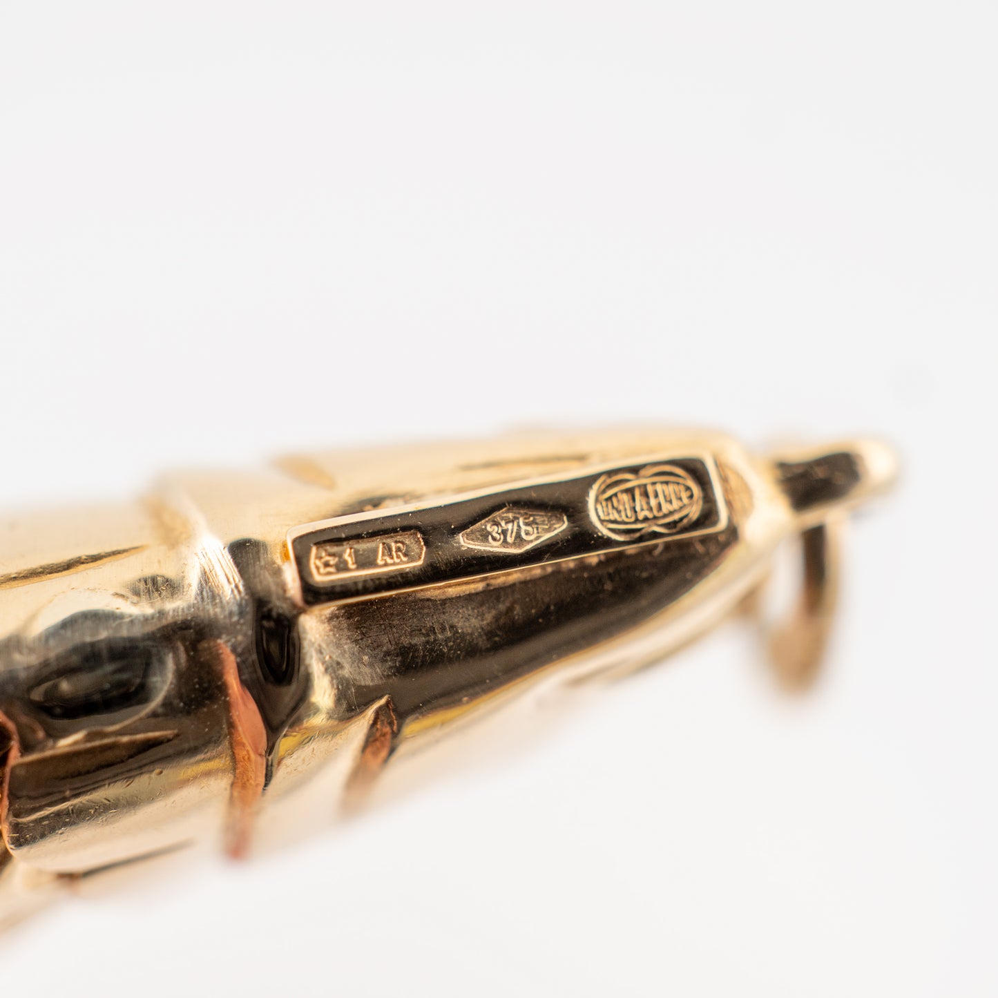 Close-up of hallmarks on articulated gold fish pendant