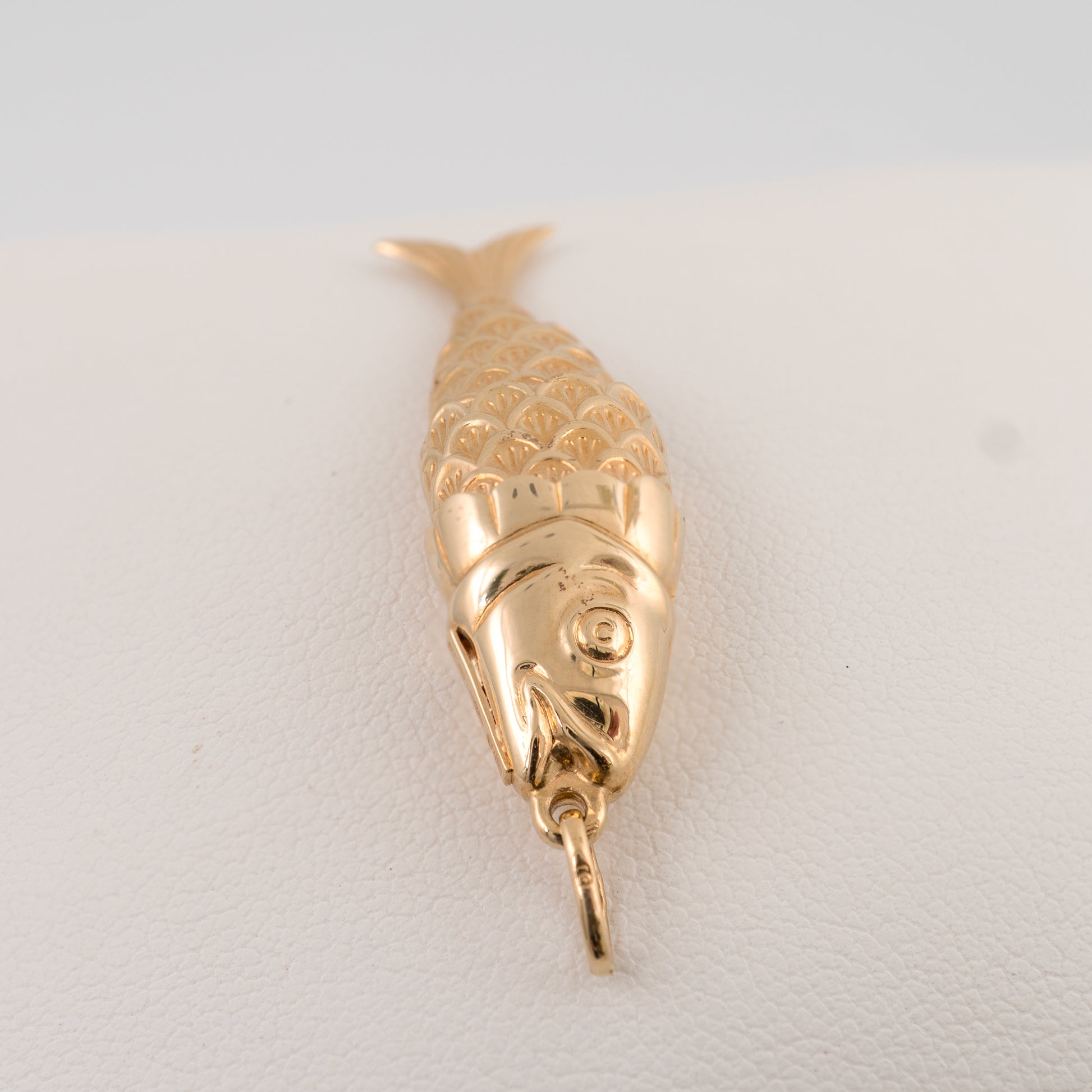 Articulated gold fish pendant photographed from top angle