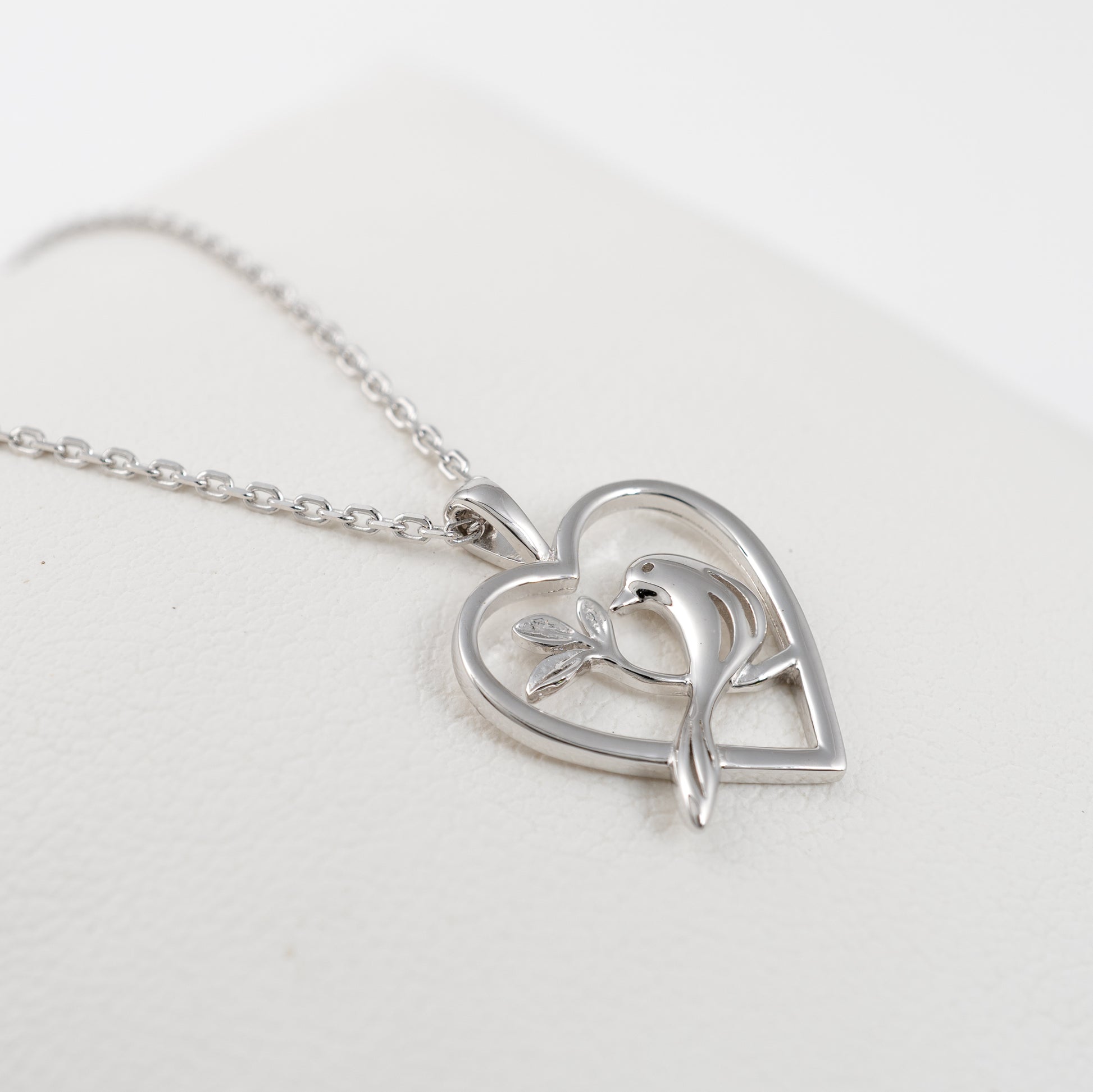 Side view of sterling silver bird necklace with heart-shaped pendant
