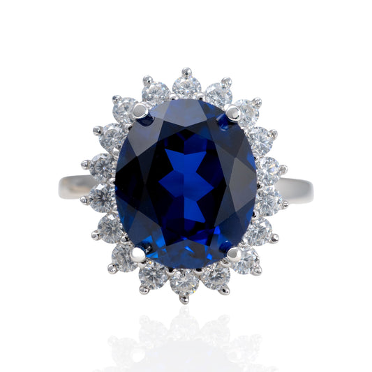Ring with a blue gemstone and diamond-studded halo on a white background