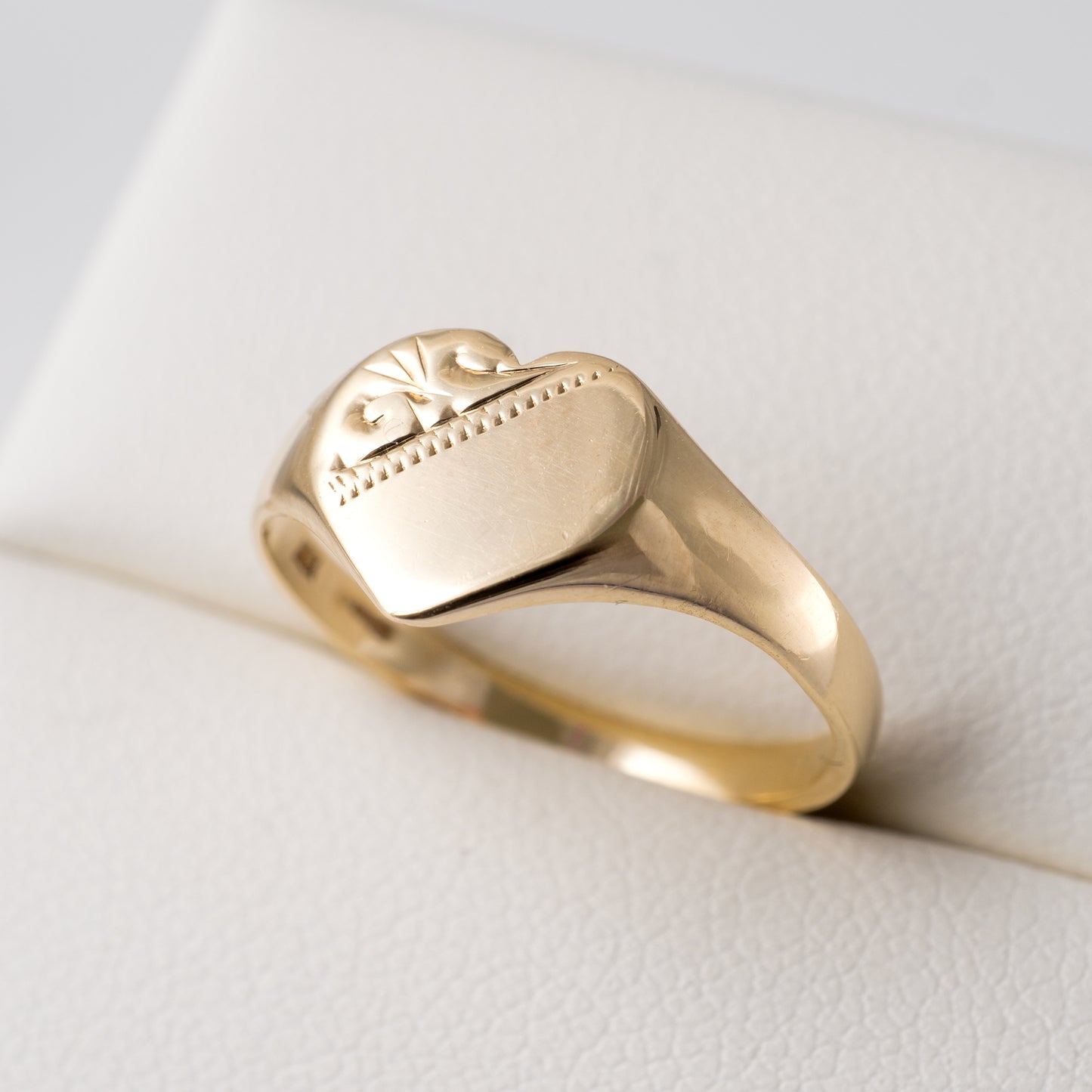 375 gold heart signet ring – angled close-up showing engraved details and polished band.