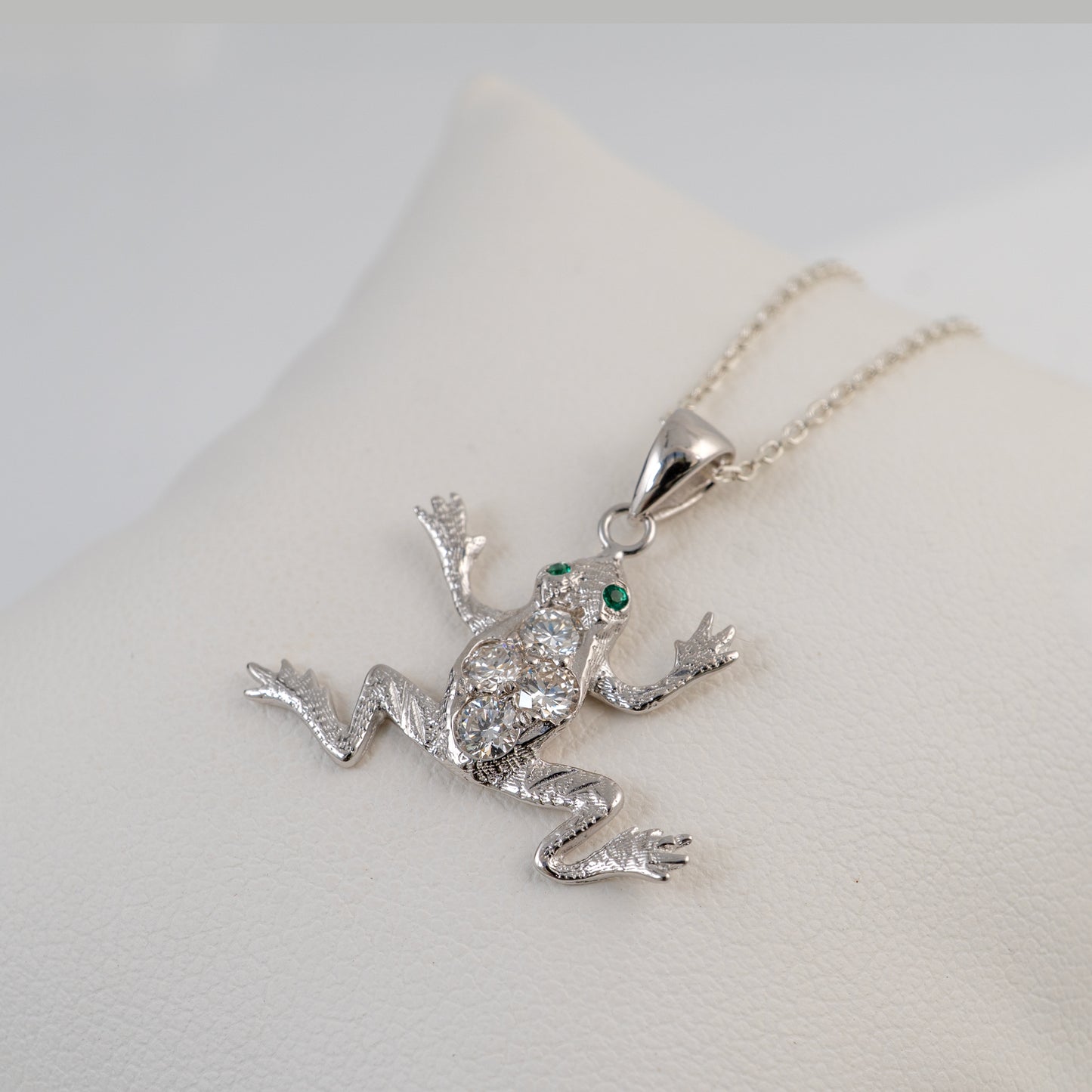 diamond frog pendant with a green gemstone on a light gray background