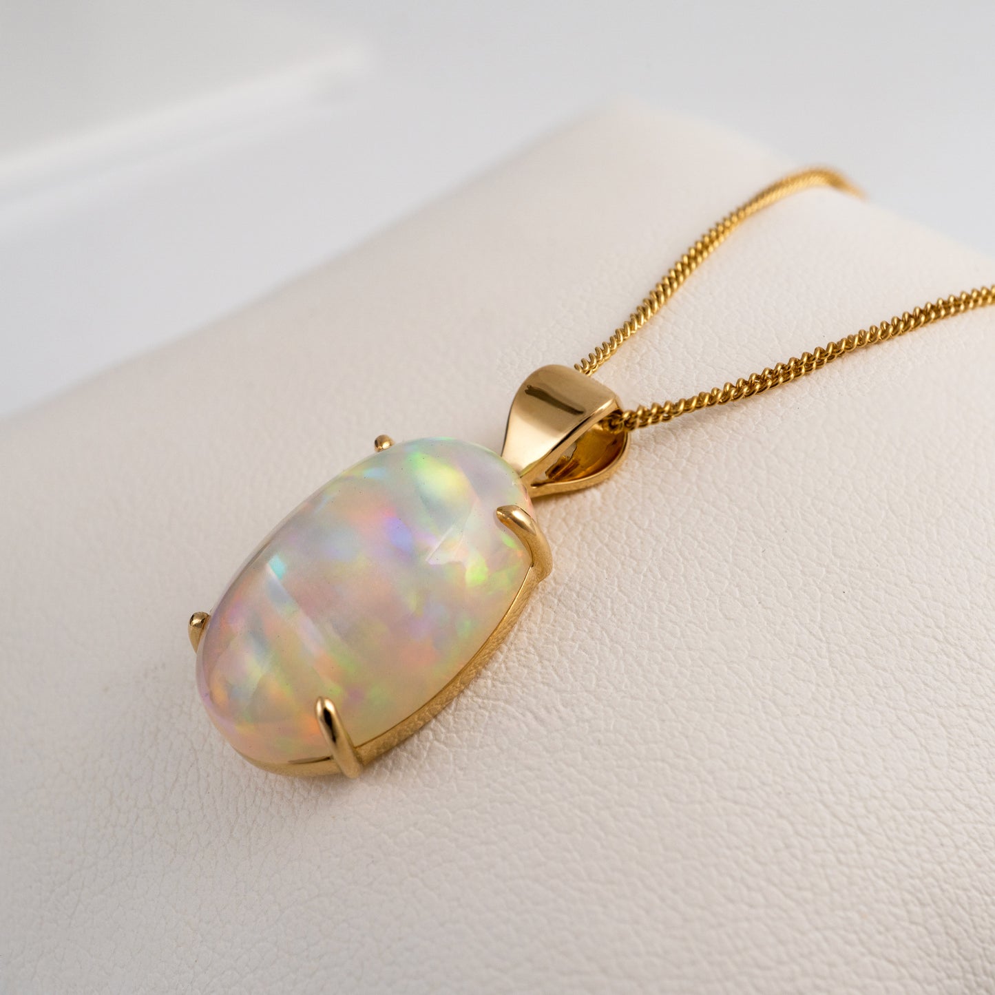 Opal pendant with gold chain on a light background