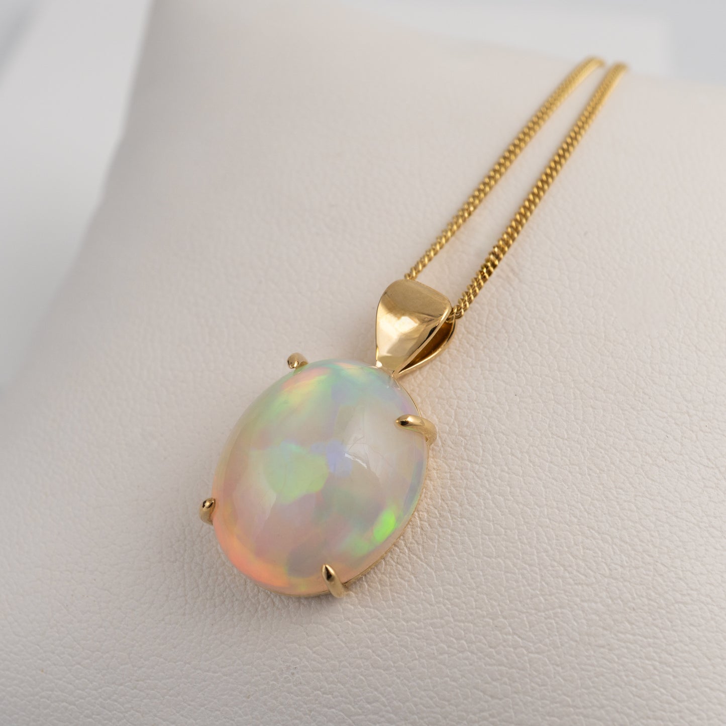 Opal pendant with gold chain on a white background