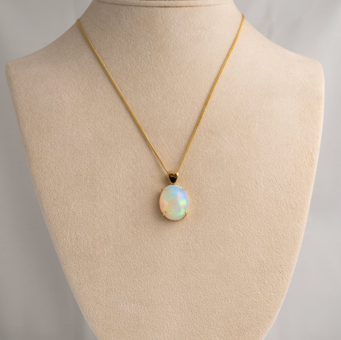 Opal pendant necklace on a mannequin bust with a plain background
