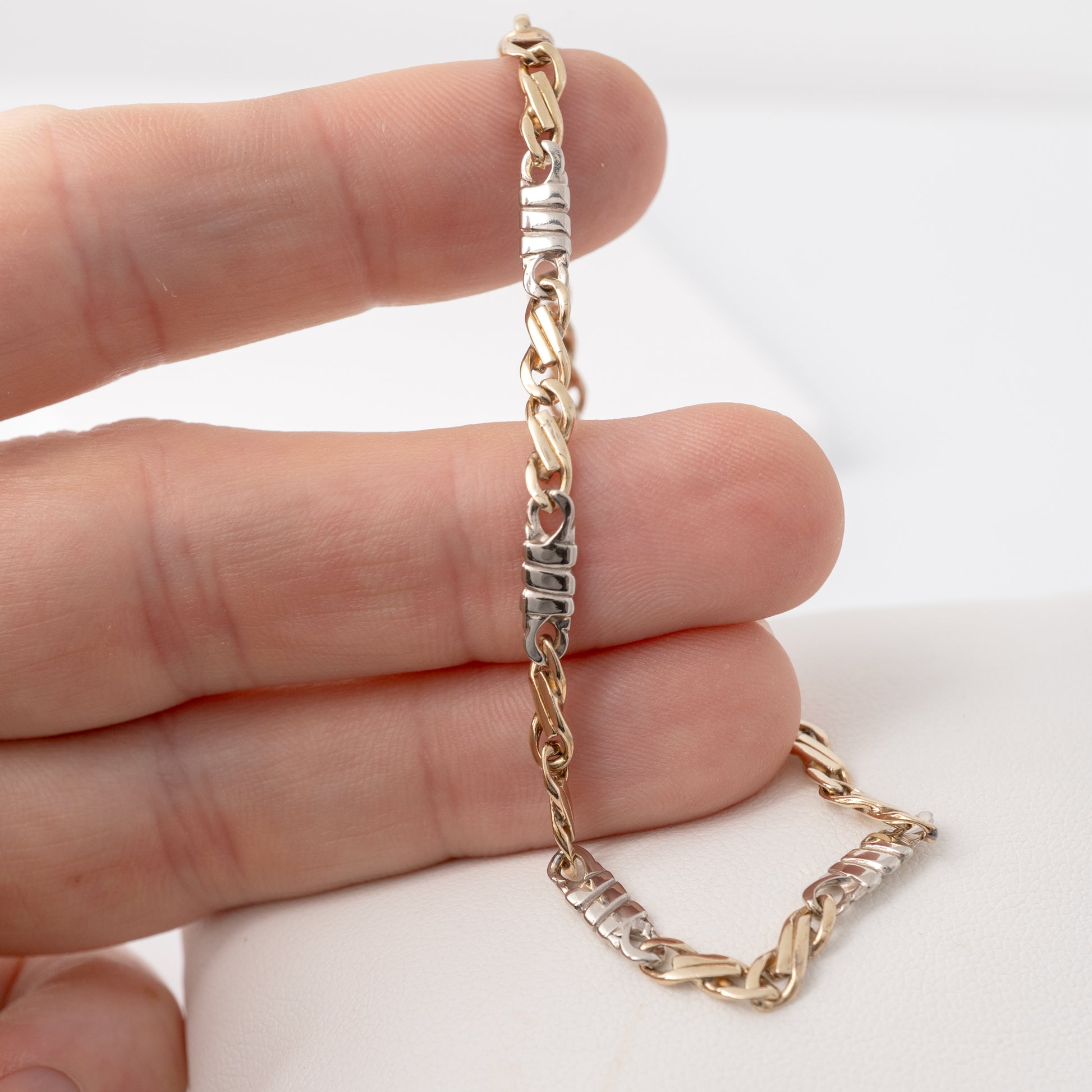 In-hand view of figaro bracelet gold showing scale and craftsmanship