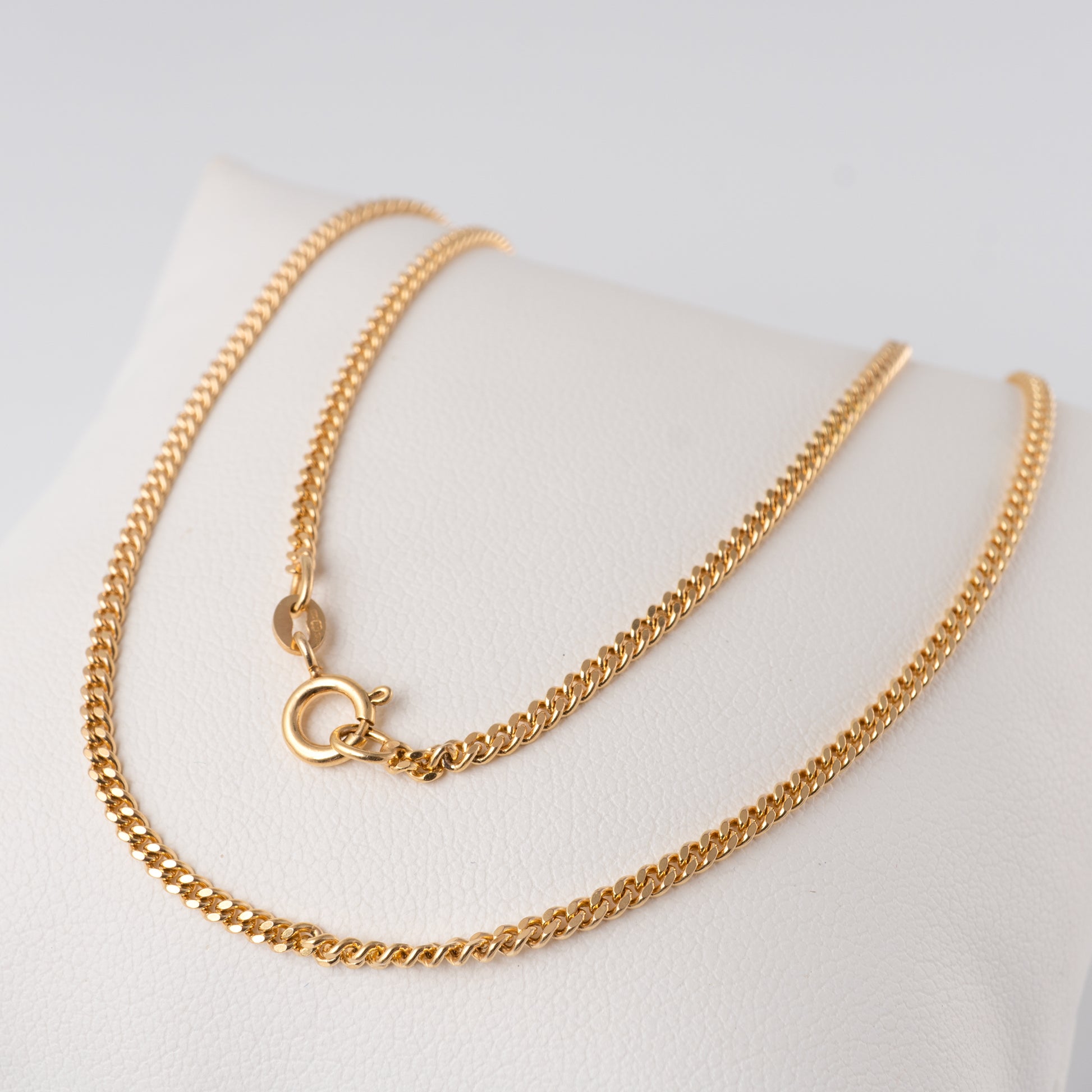 9ct gold flat curb link necklace displayed on white stand, showing spring ring clasp