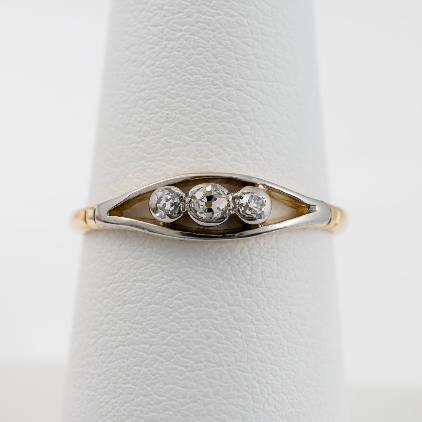 Detailed close-up of open ellipse design on vintage diamond ring with three bezel set old-cut diamonds