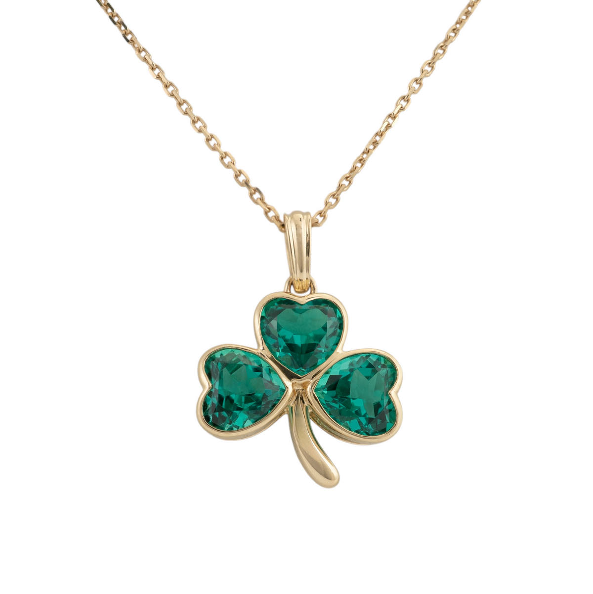 Gold shamrock necklace in 9ct yellow gold with three heart-cut lab-grown emeralds in bezel settings, shown on a gold chain against a white background.