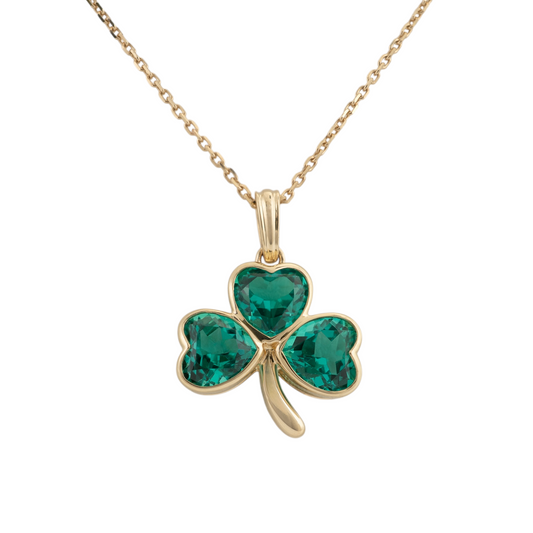 Gold shamrock necklace in 9ct yellow gold with three heart-cut lab-grown emeralds in bezel settings, shown on a gold chain against a white background.