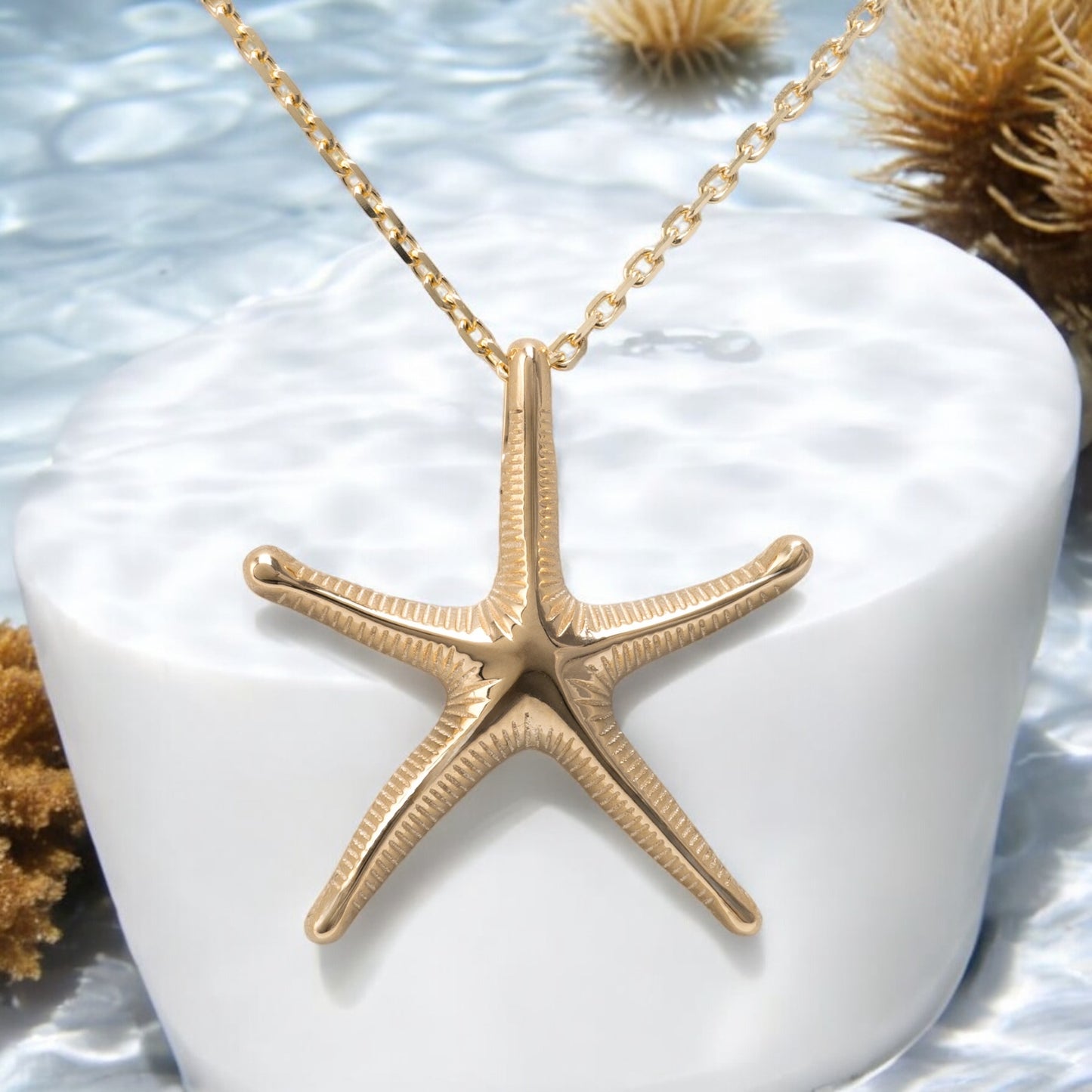 gold starfish necklace displayed under the water with coral ref and natural light unique design by hunters fine jewellery