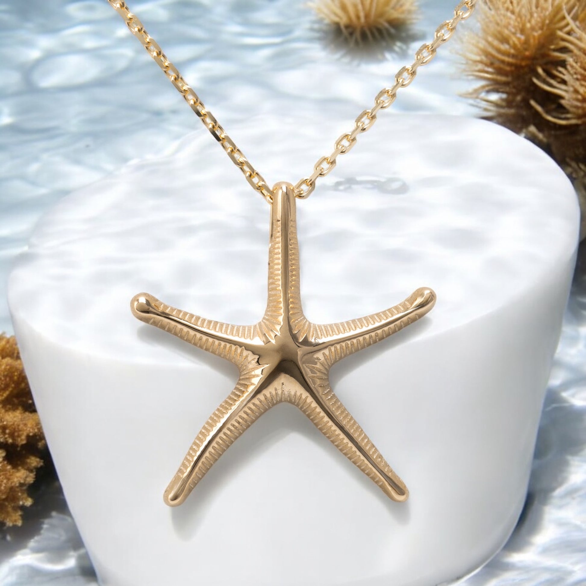 gold starfish necklace displayed under the water with coral ref and natural light unique design by hunters fine jewellery