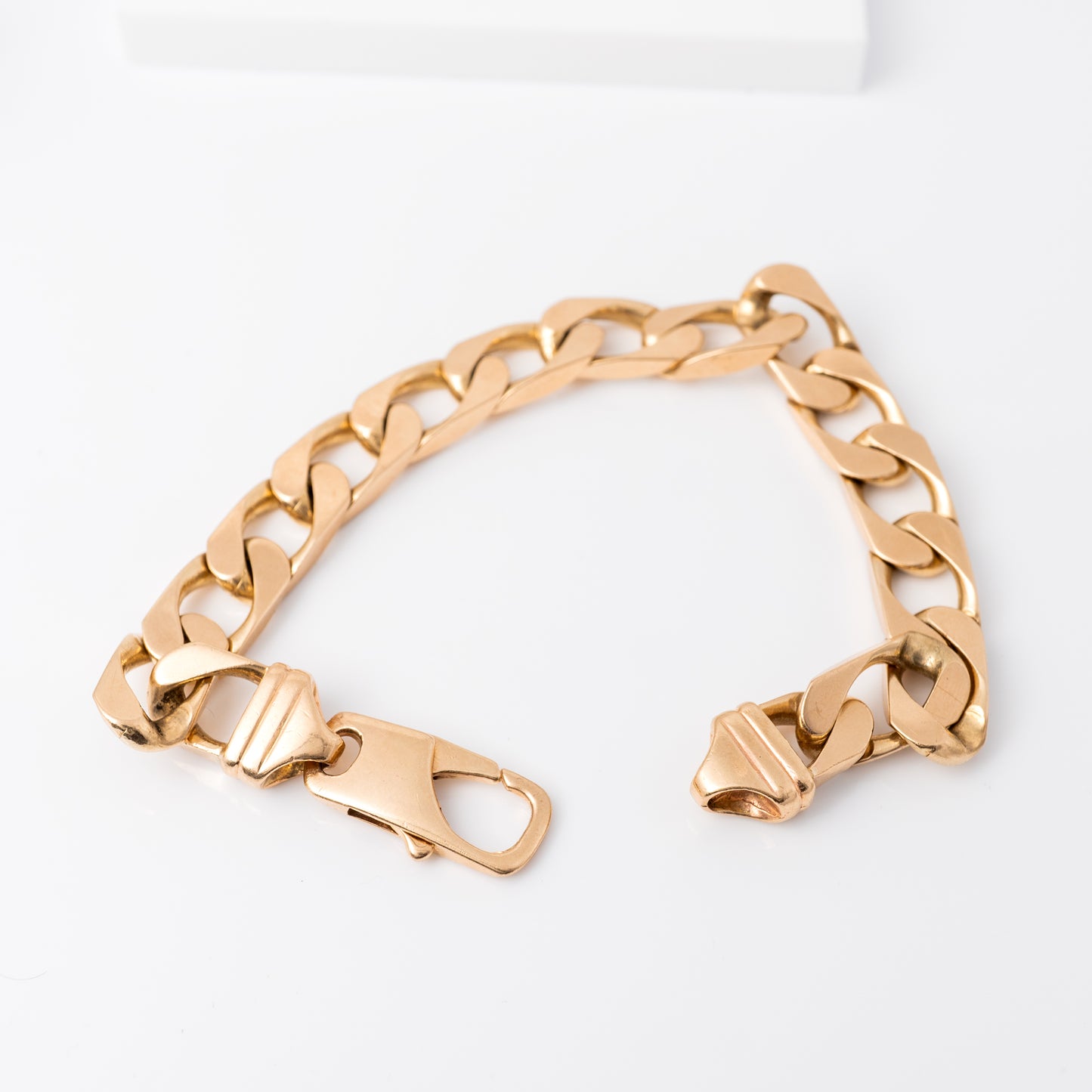 mens heavy gold curb bracelet held in hand, showcasing sturdy lobster clasp