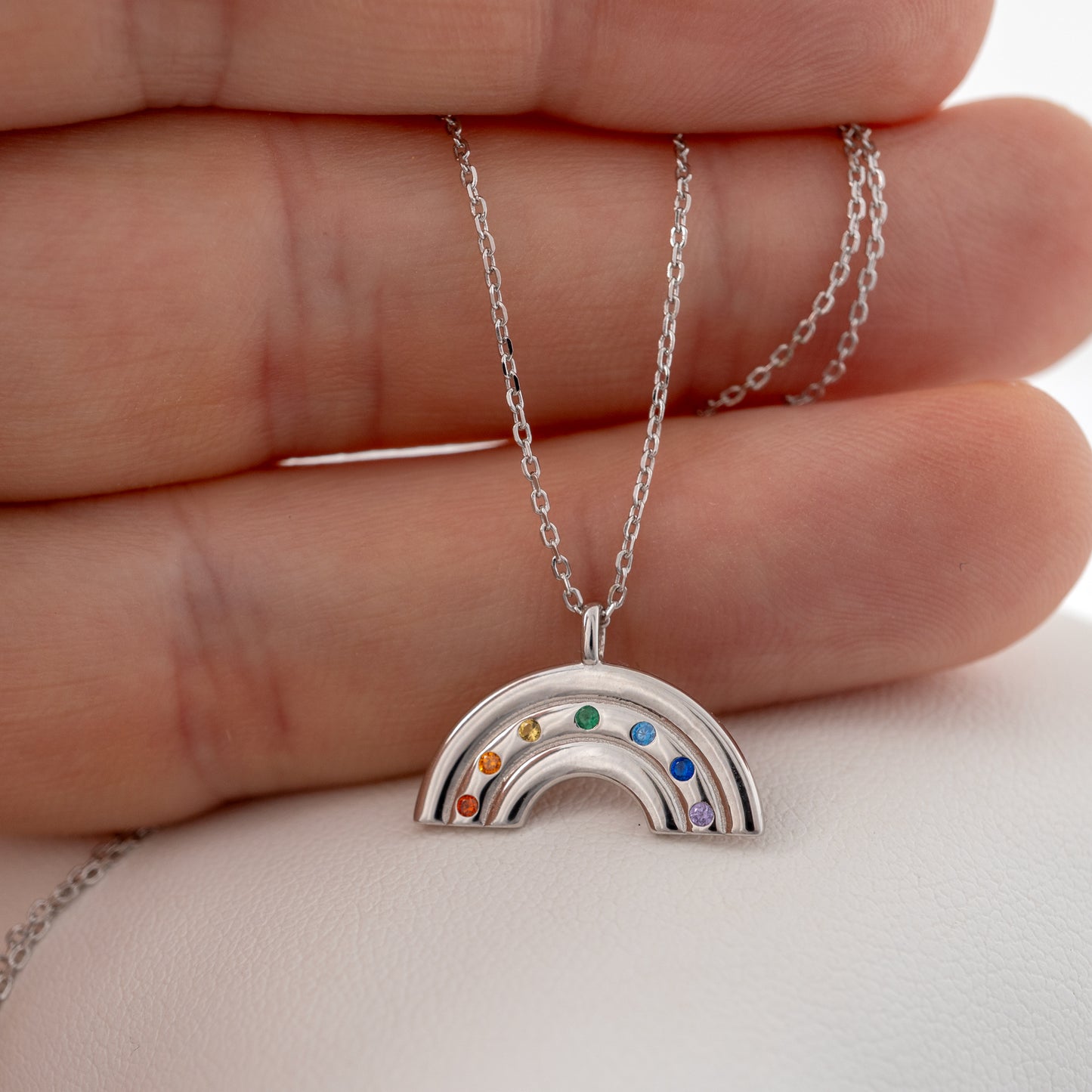 Silver rainbow necklace with rainbow colours, shown in hand – Hunters Fine Jewellery