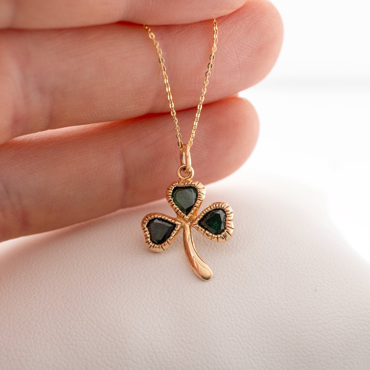 Gold shamrock necklace held in hand, highlighting its size and craftsmanship