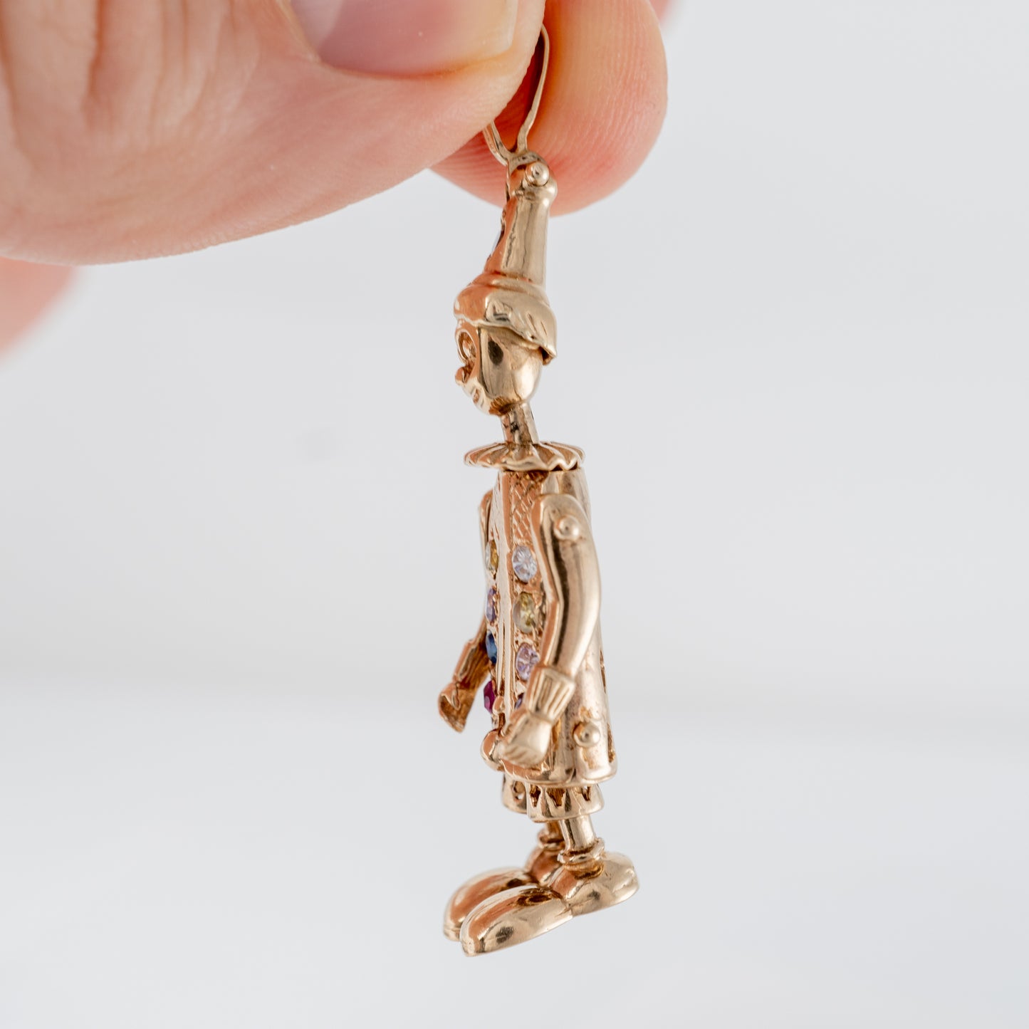 holding an articulated gold clown necklace showing the side