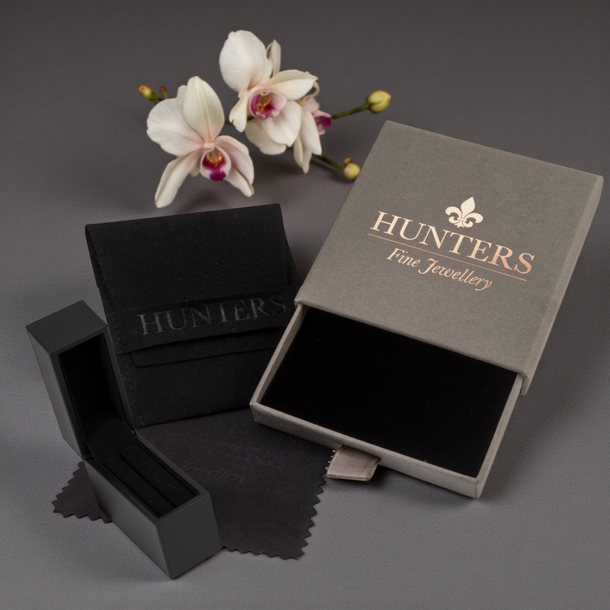 Jewellery boxes with 'Hunters Fine Jewellery' branding on a dark background with flowers.