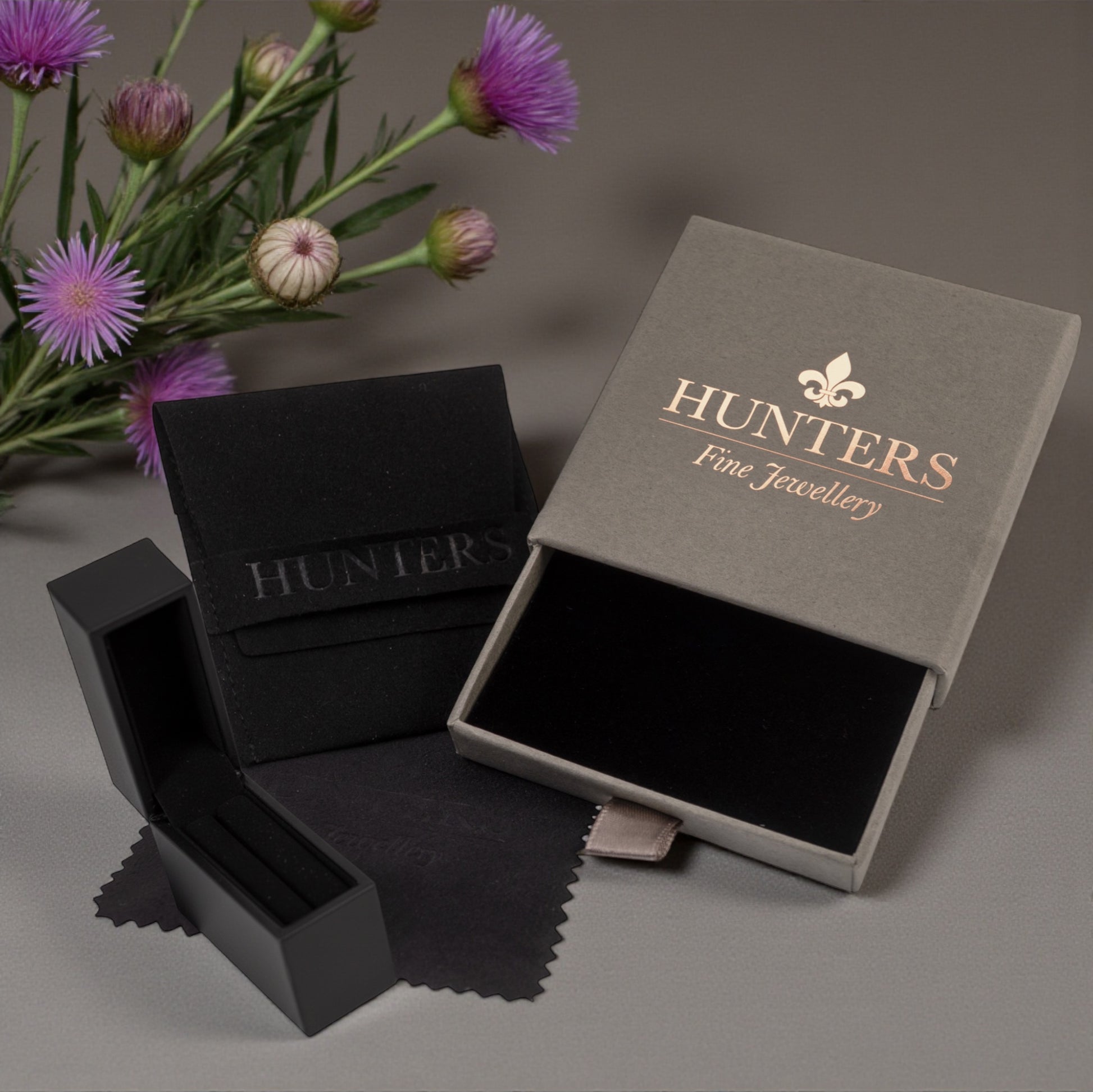 Jewelry box with 'Hunters Fine Jewellery' branding on a gray background with flowers.