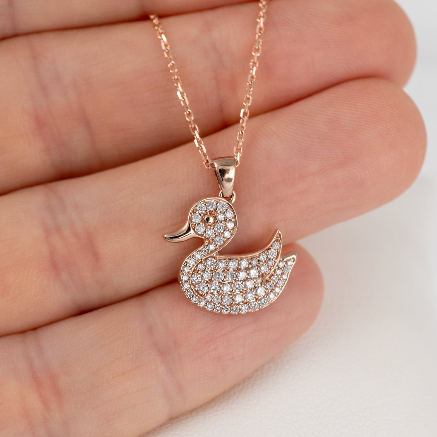 Lab grown diamond duck necklace in rose gold persons hand