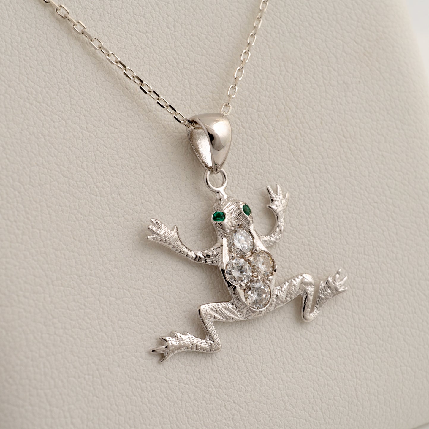 diamond frog pendant with green eyes on a chain against a light gray background