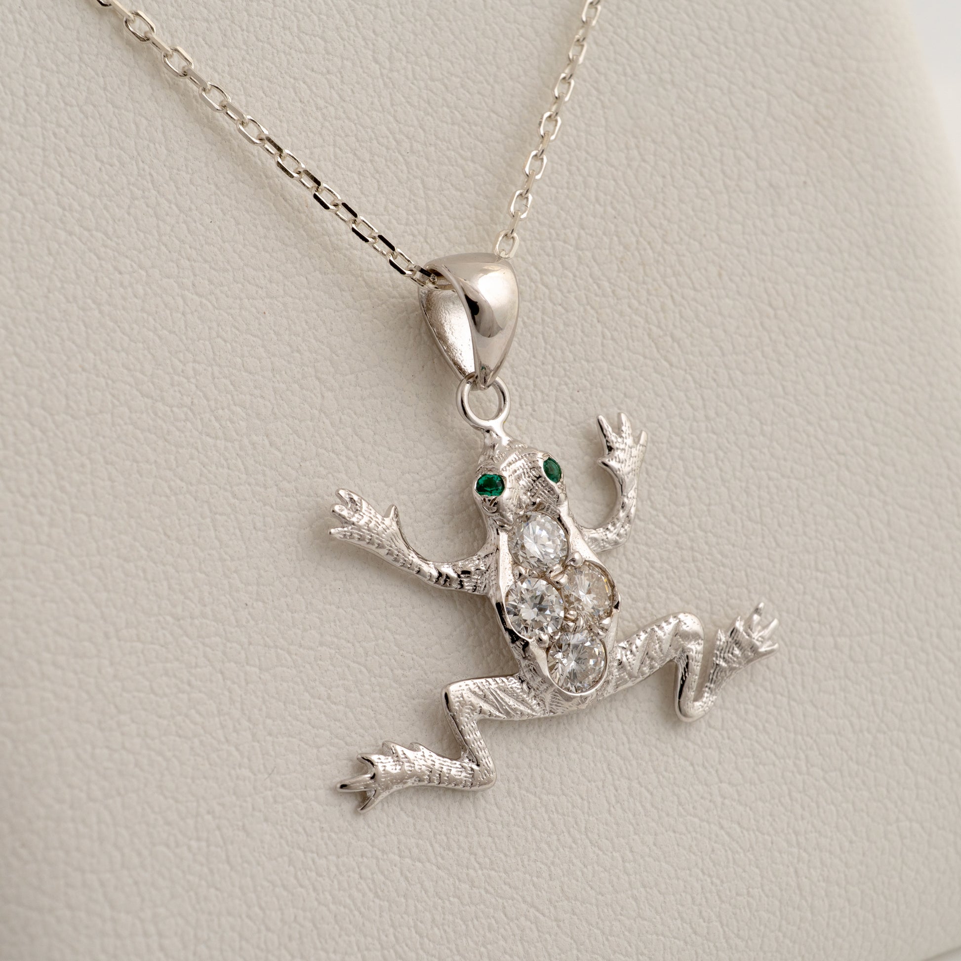 diamond frog pendant with green eyes on a chain against a light gray background