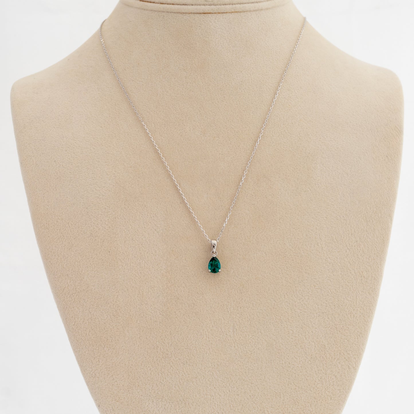 Necklace with a lab emerald pendant on a mannequin bust against a white background