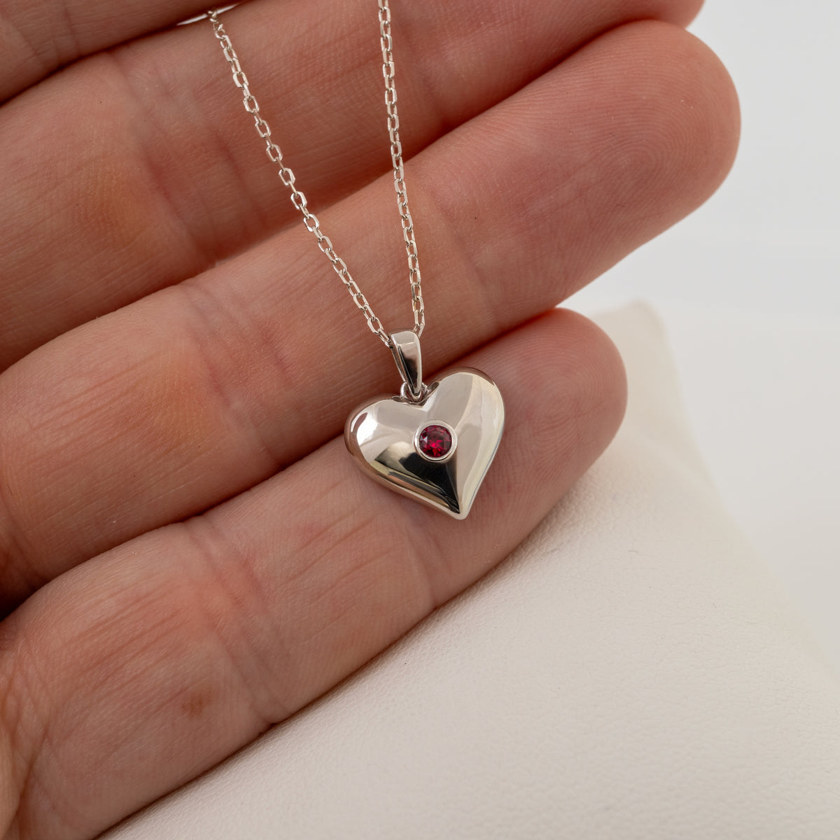 Lab-grown ruby silver heart necklace shown in hand to illustrate pendant size
