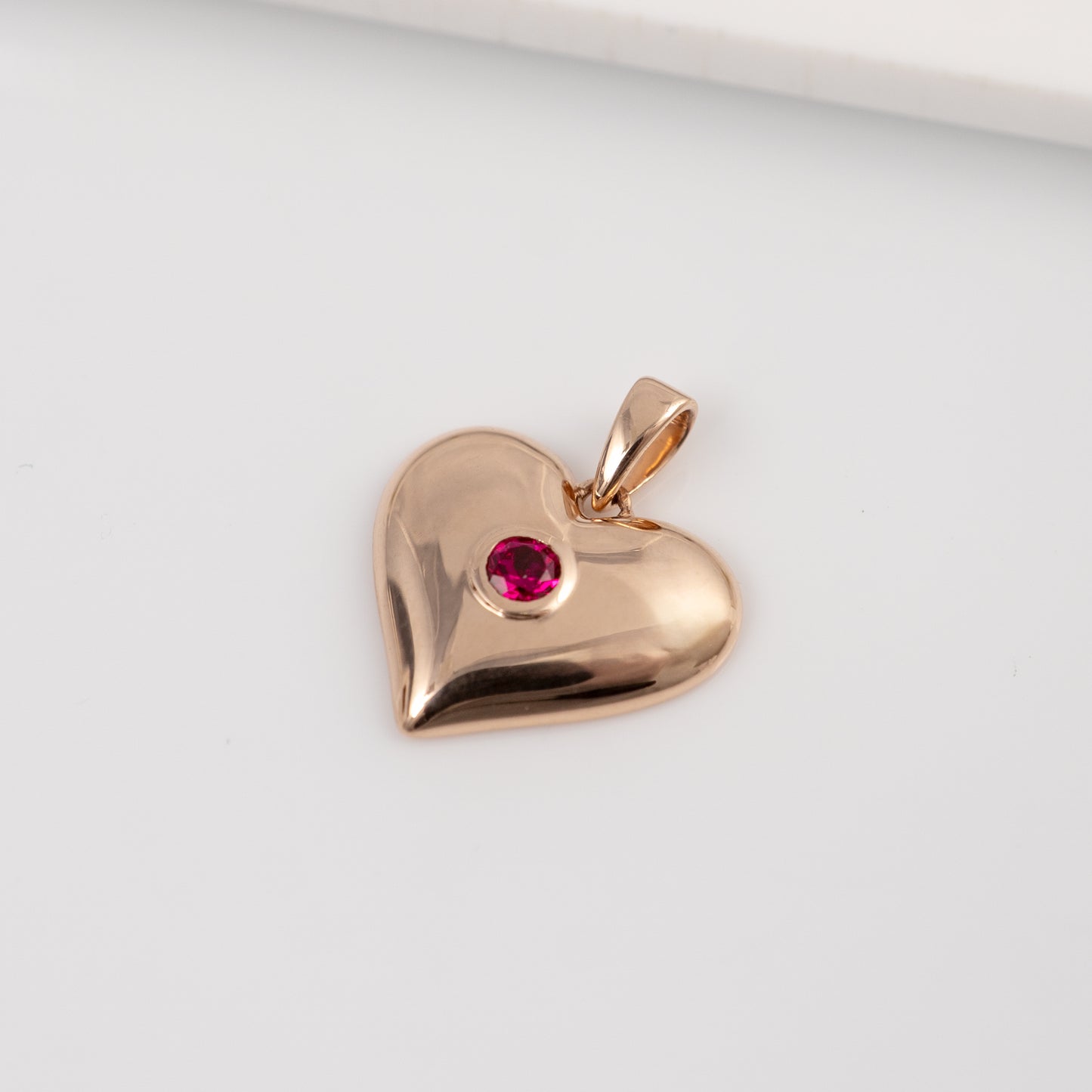 Close-up of lab ruby heart pendant in 9ct, 375  rose gold showing bezel-set ruby detail