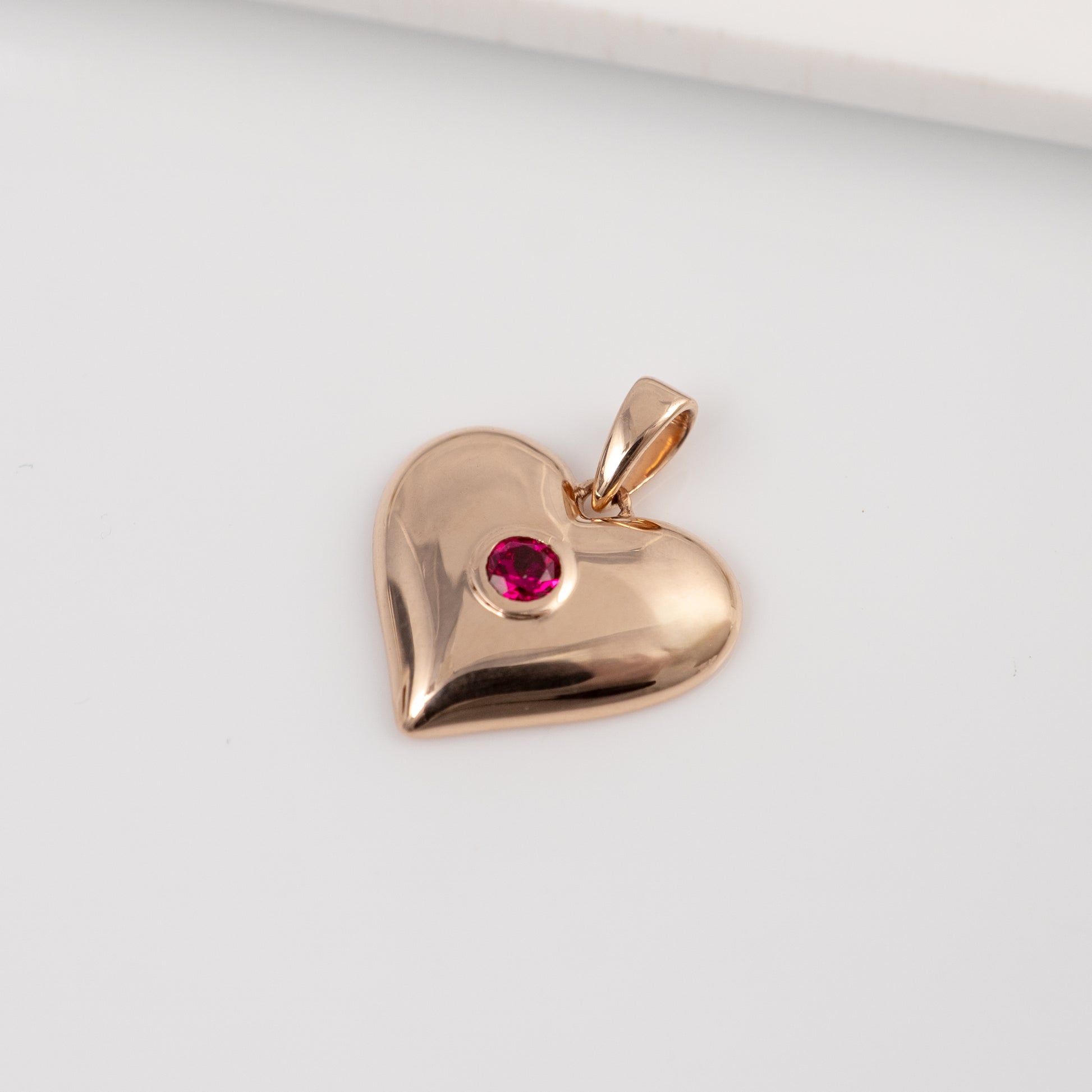 Close-up of lab ruby heart pendant in 9ct, 375  rose gold showing bezel-set ruby detail