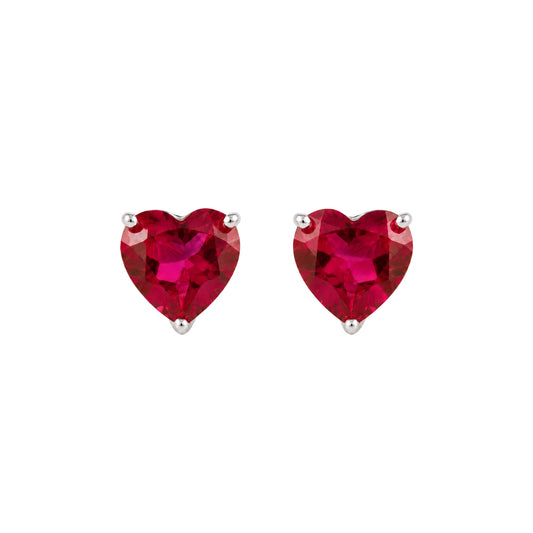A pair of heart-shaped stud earrings featuring vibrant lab ruby heart-cut gemstones in silver prong settings, shown against a plain white background.