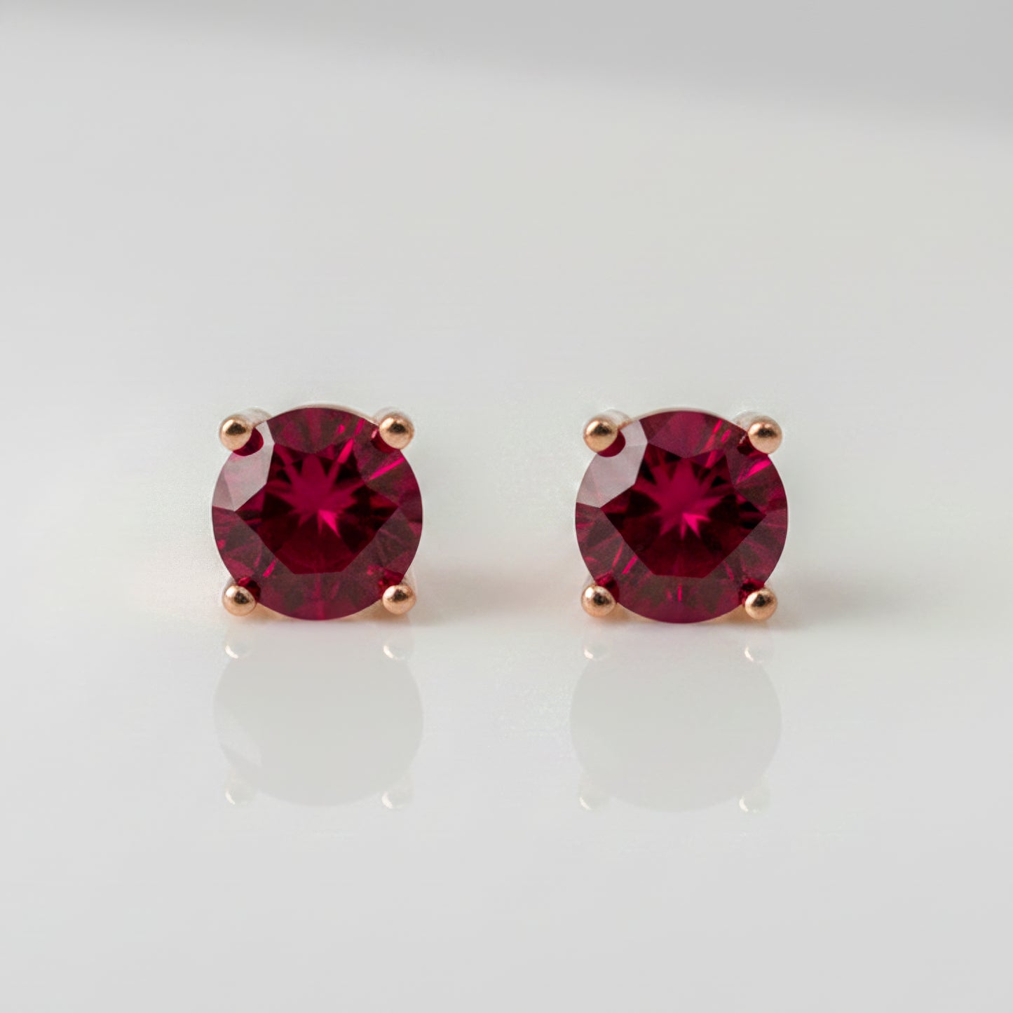 Pair of lab ruby stud earrings on a light gray background