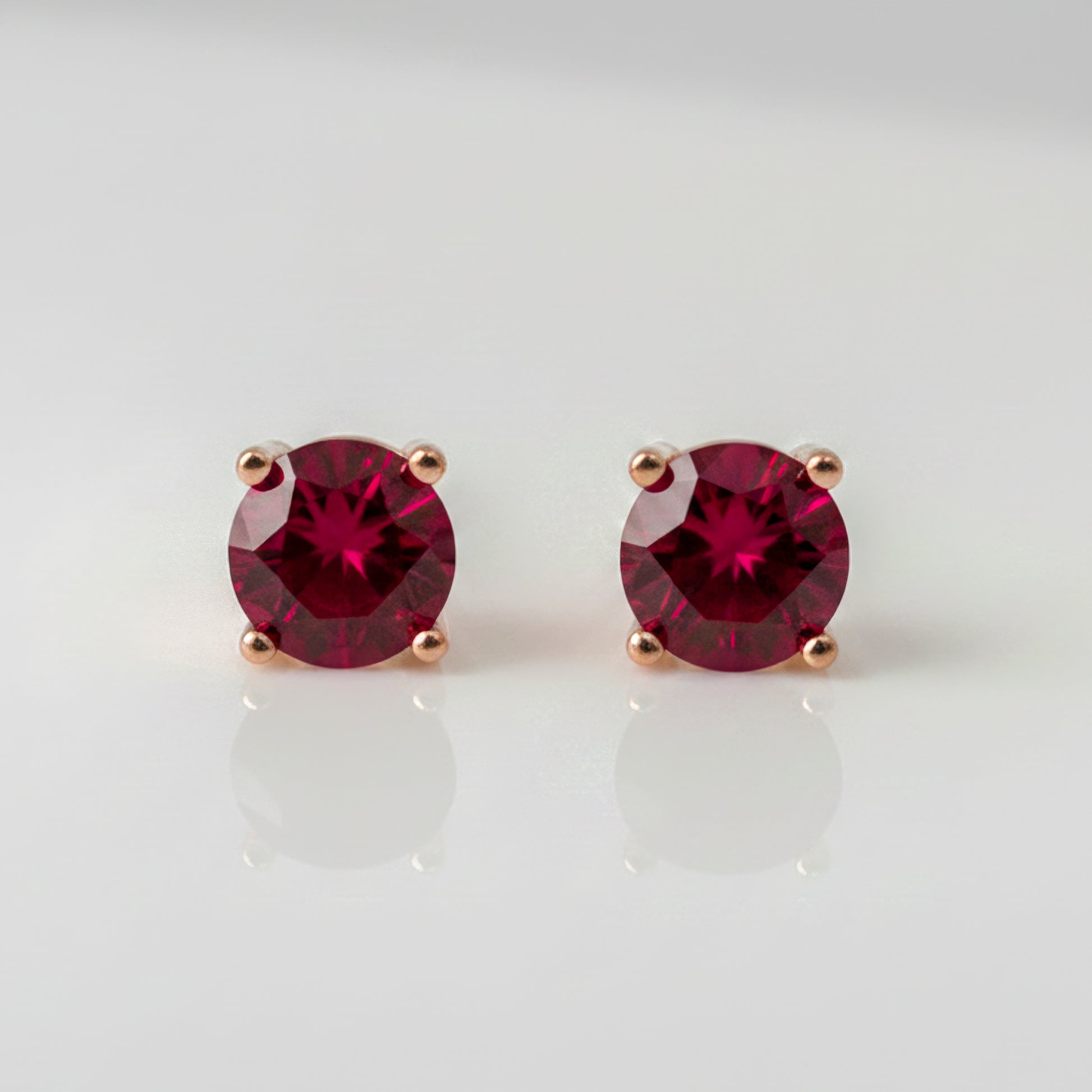 Pair of lab ruby stud earrings on a light gray background