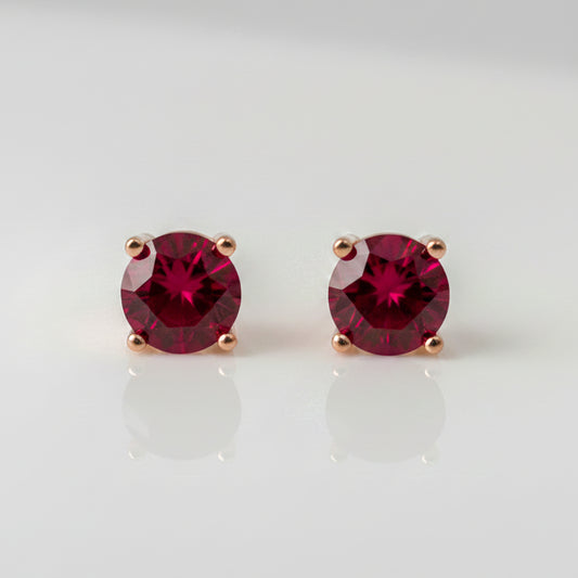 Pair of lab ruby stud earrings on a light gray background
