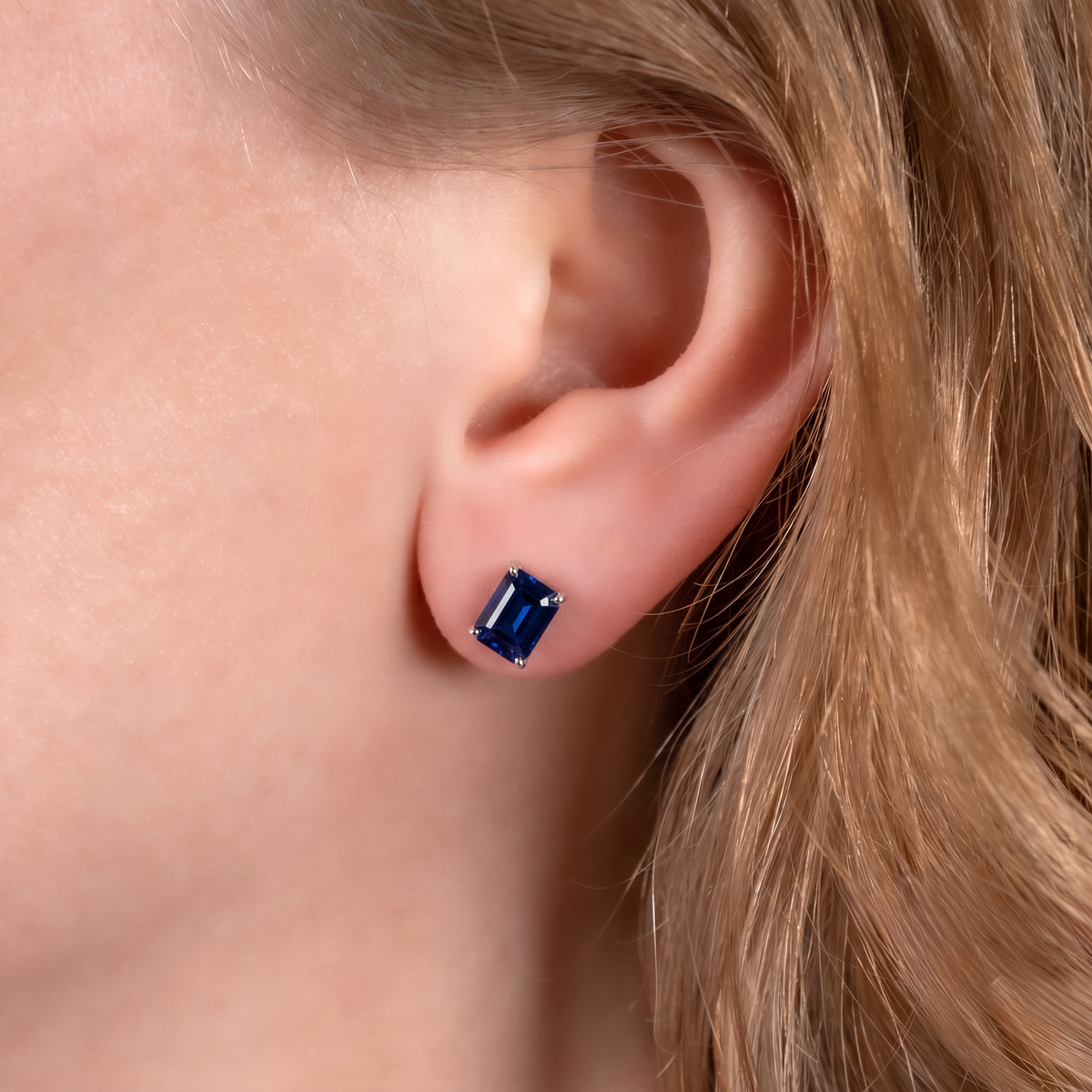 Royal blue lab sapphire rectangle stud earring in sterling silver worn on the ear