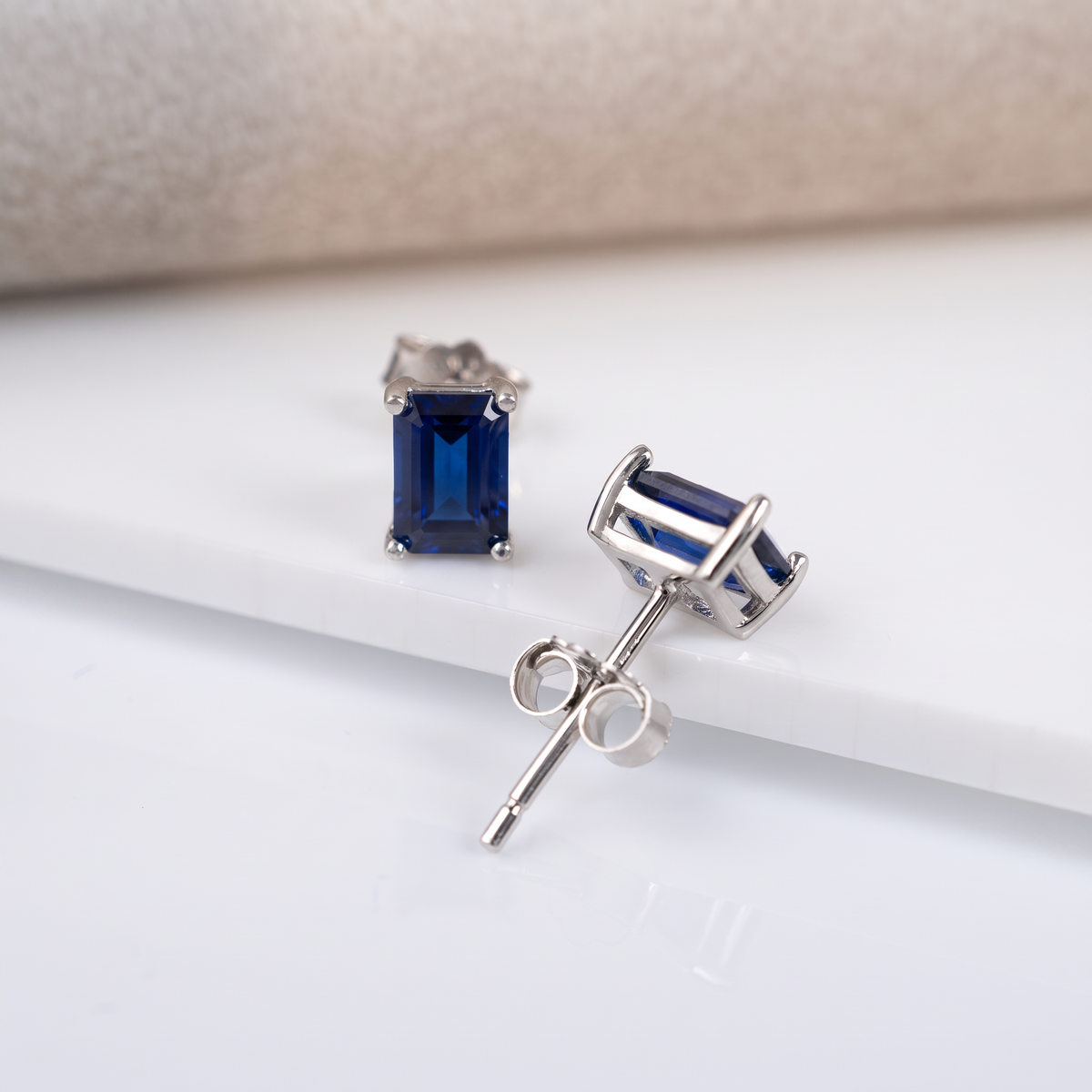 Lab sapphire rectangle stud earrings showing the silver post, four-claw setting and butterfly back