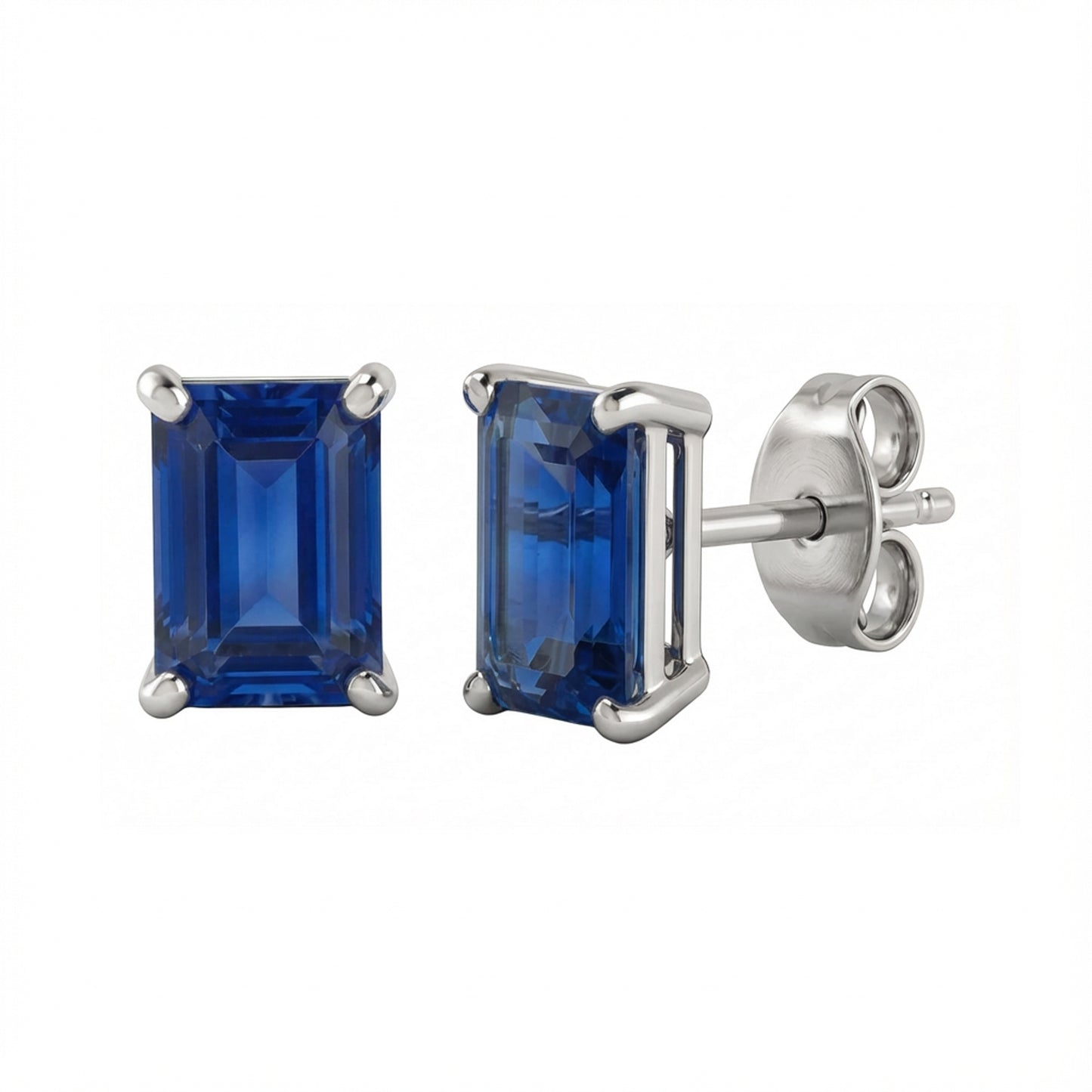 A pair of rectangular emerald-cut lab blue sapphire stud earrings in a silver-toned metal setting, with one earring facing forward and the other angled to show the post and butterfly back, on a plain white background.