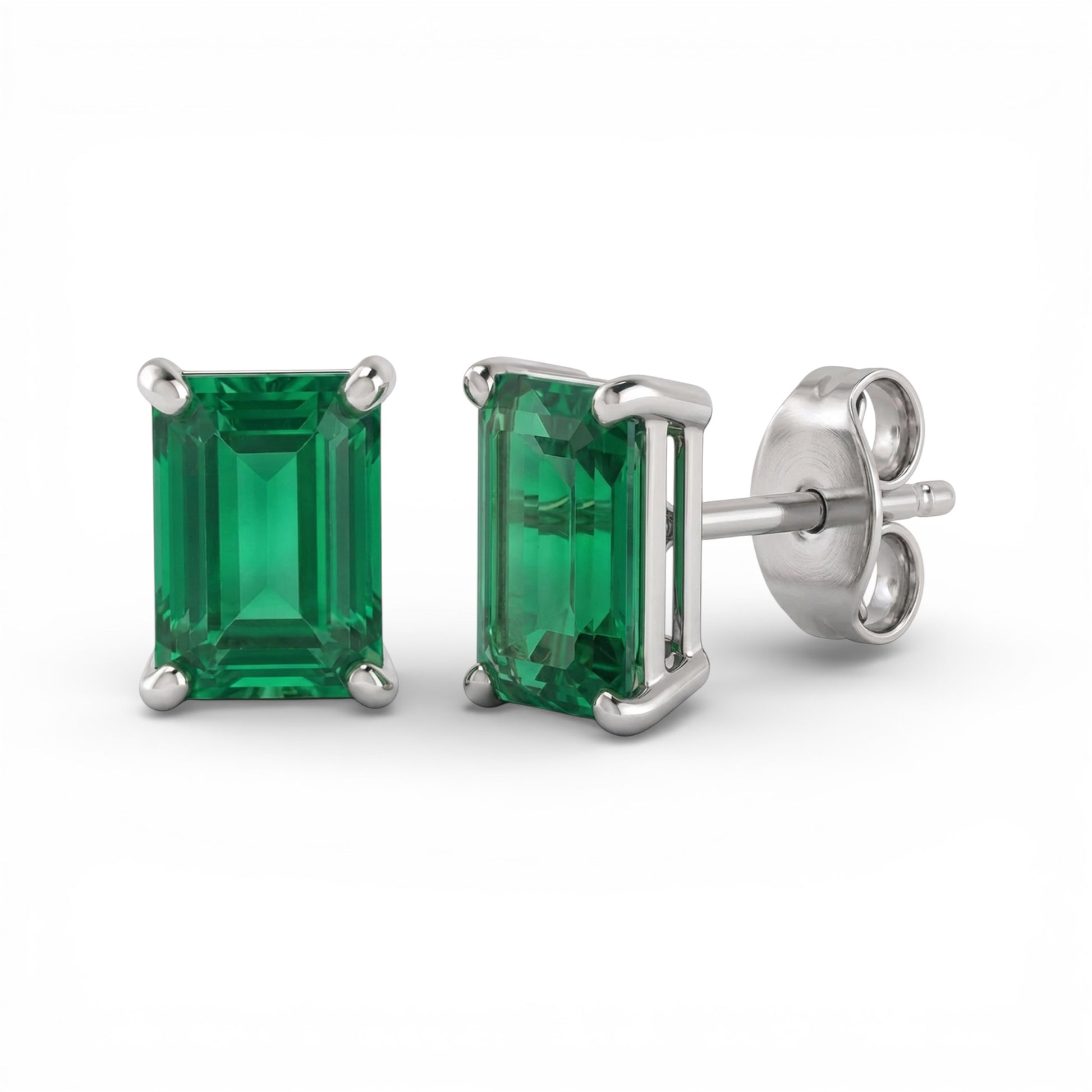 Pair of 4x6mm rectangle cut lab emerald stud earrings with silver settings on a white background