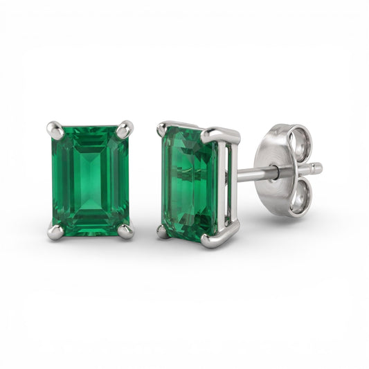 Pair of 4x6mm rectangle cut lab emerald stud earrings with silver settings on a white background