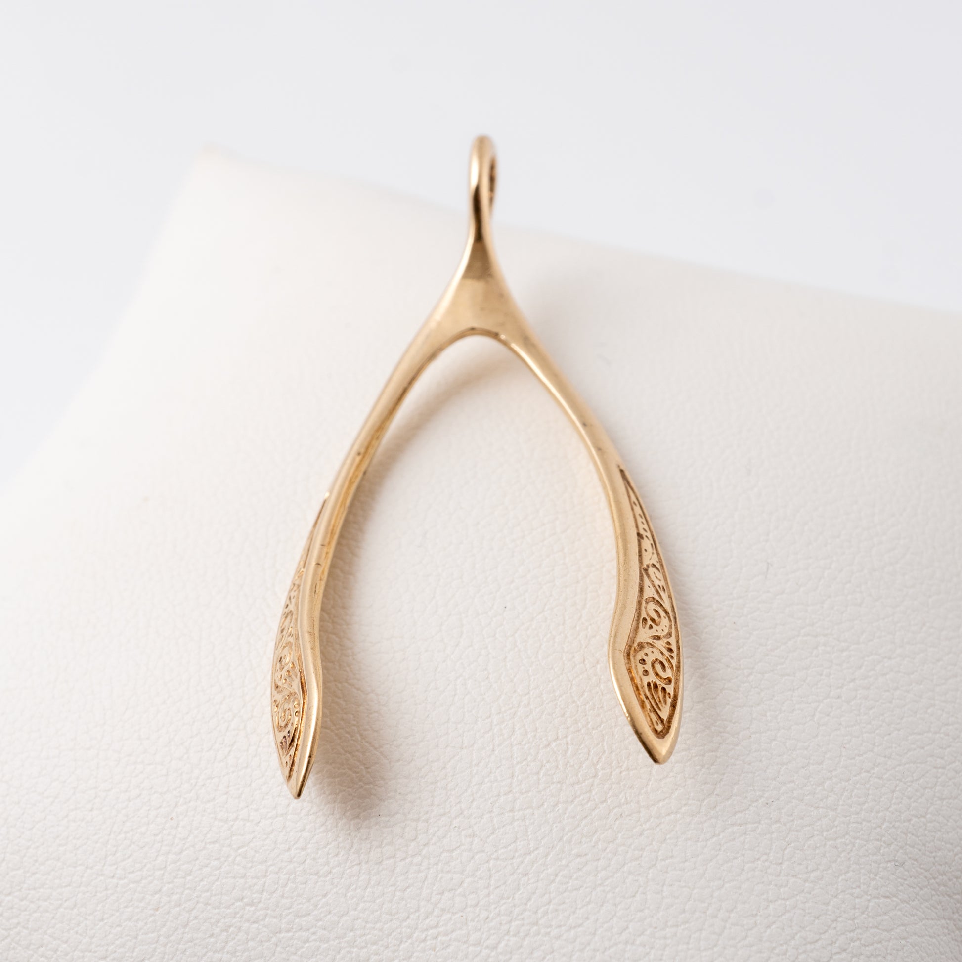 Large vintage gold wishbone pendant displayed on a white background, showcasing scroll detailing on both sides