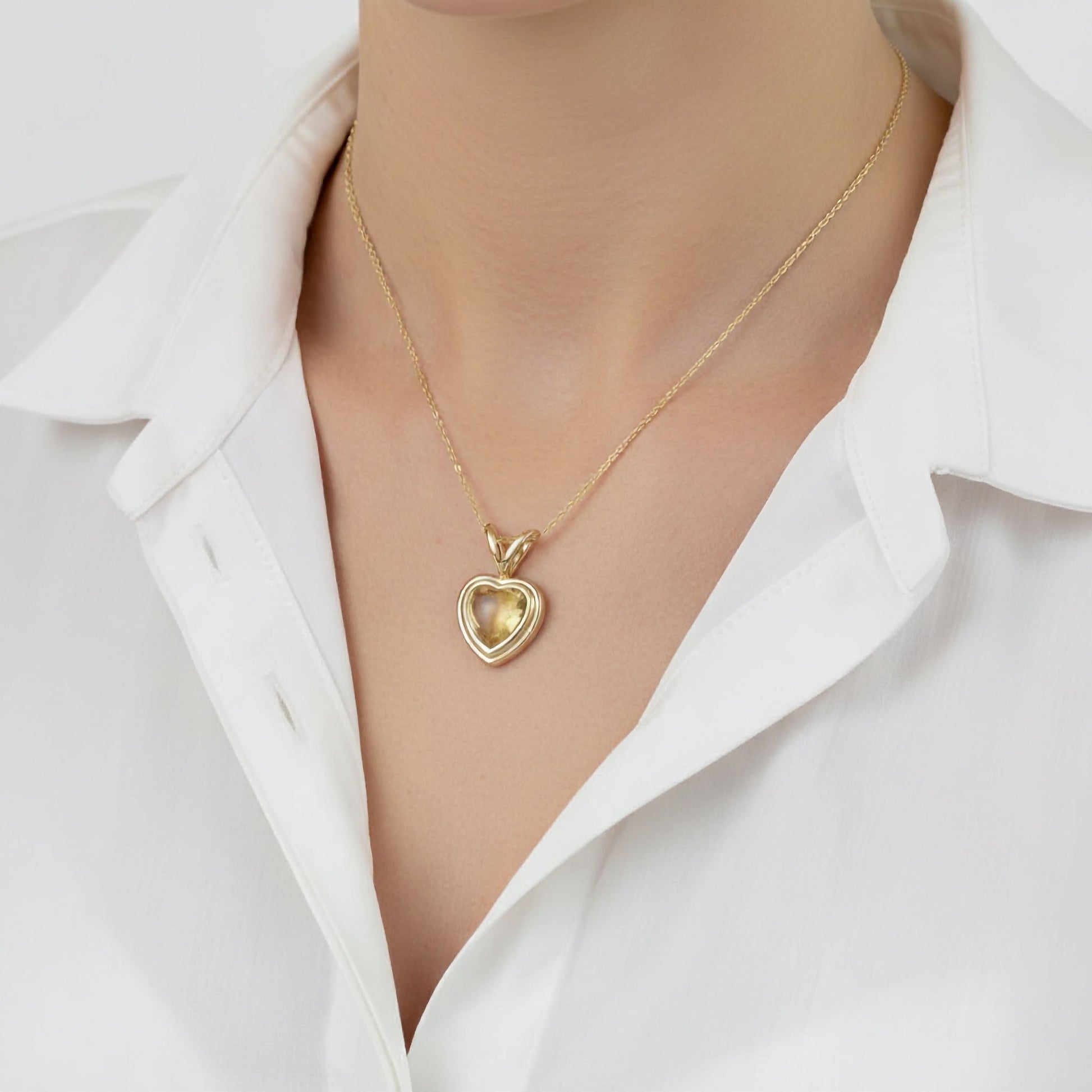 Gold heart-shaped necklace on a mannequin with a white shirt