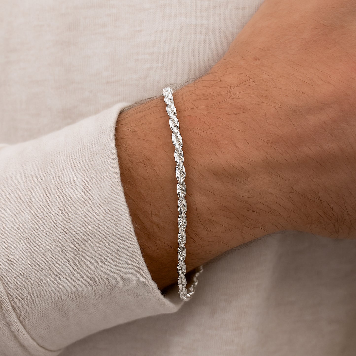 Silver 3mm rope bracelet on a mans wrist with a neutral background