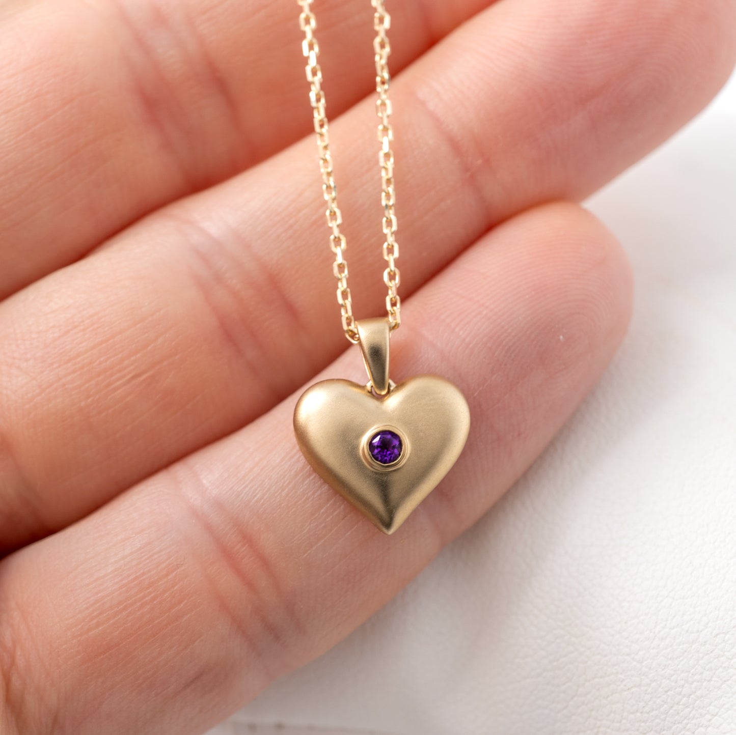 holding an amethyst heart necklace showing the matte finish and rounded edges and scale