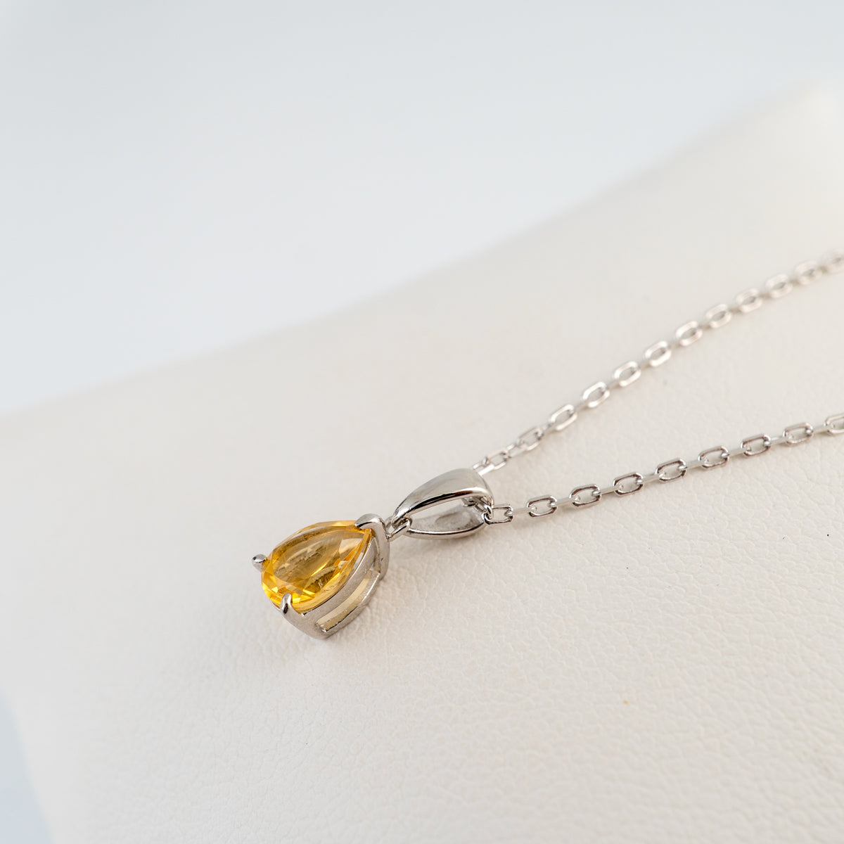 Side angle of the natural citrine teardrop necklace showing the silver setting and bail.