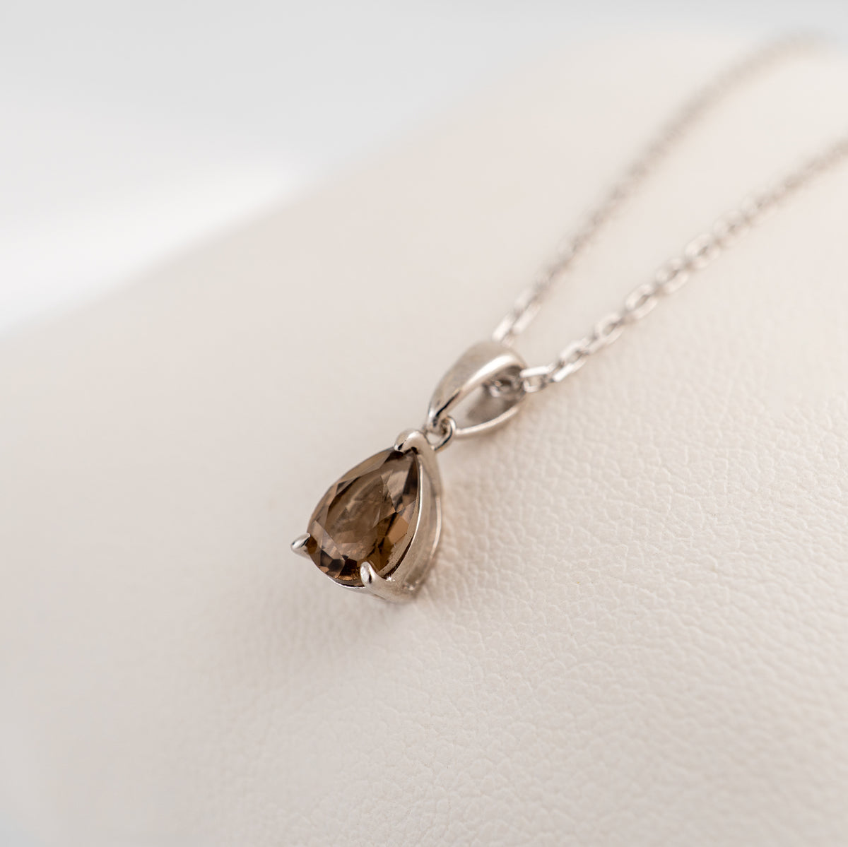 Slight angled view of a natural smoky quartz teardrop pendant, showing the brown gemstone colour and sterling silver setting.